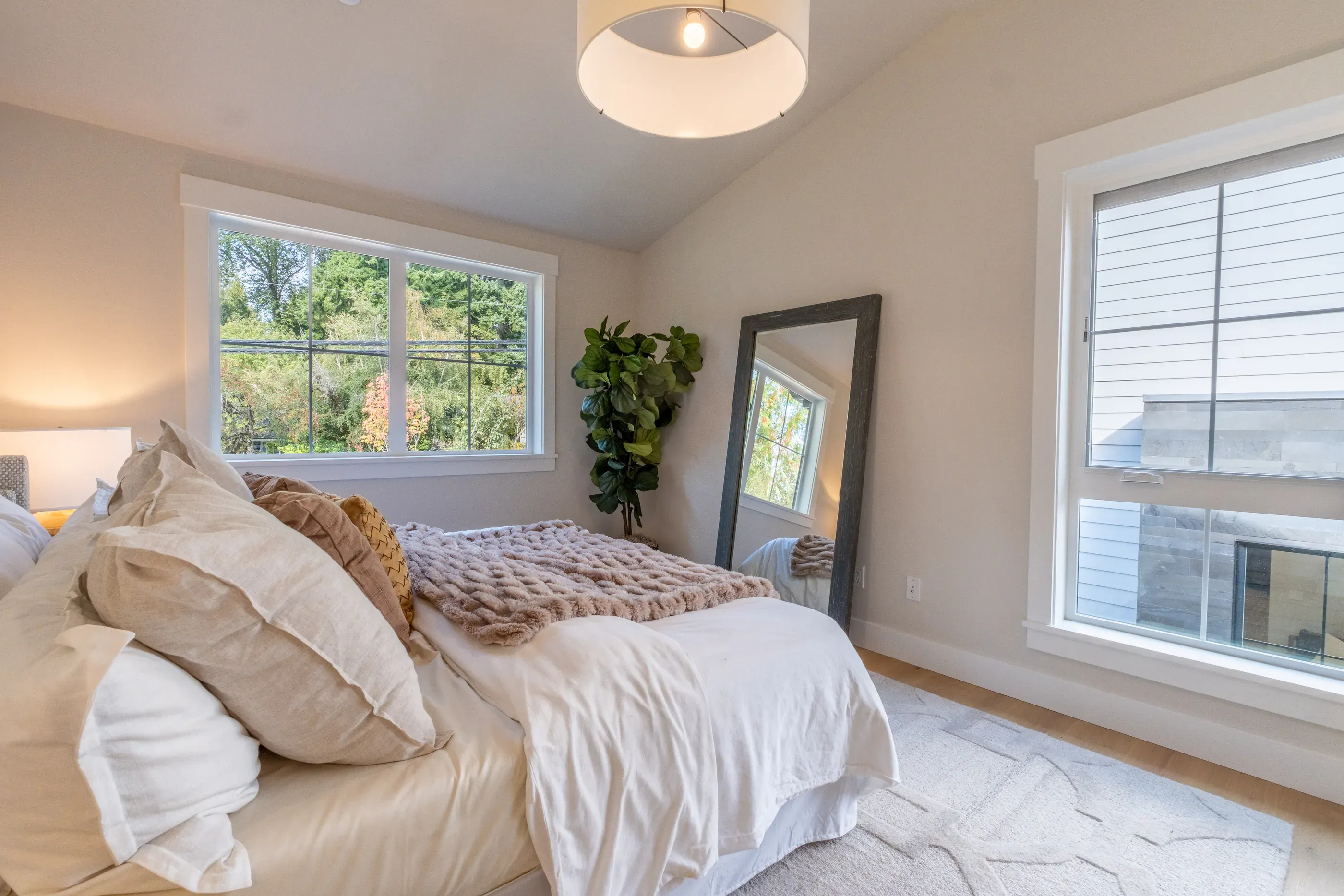 Bright bedroom with white bedding and large windows.