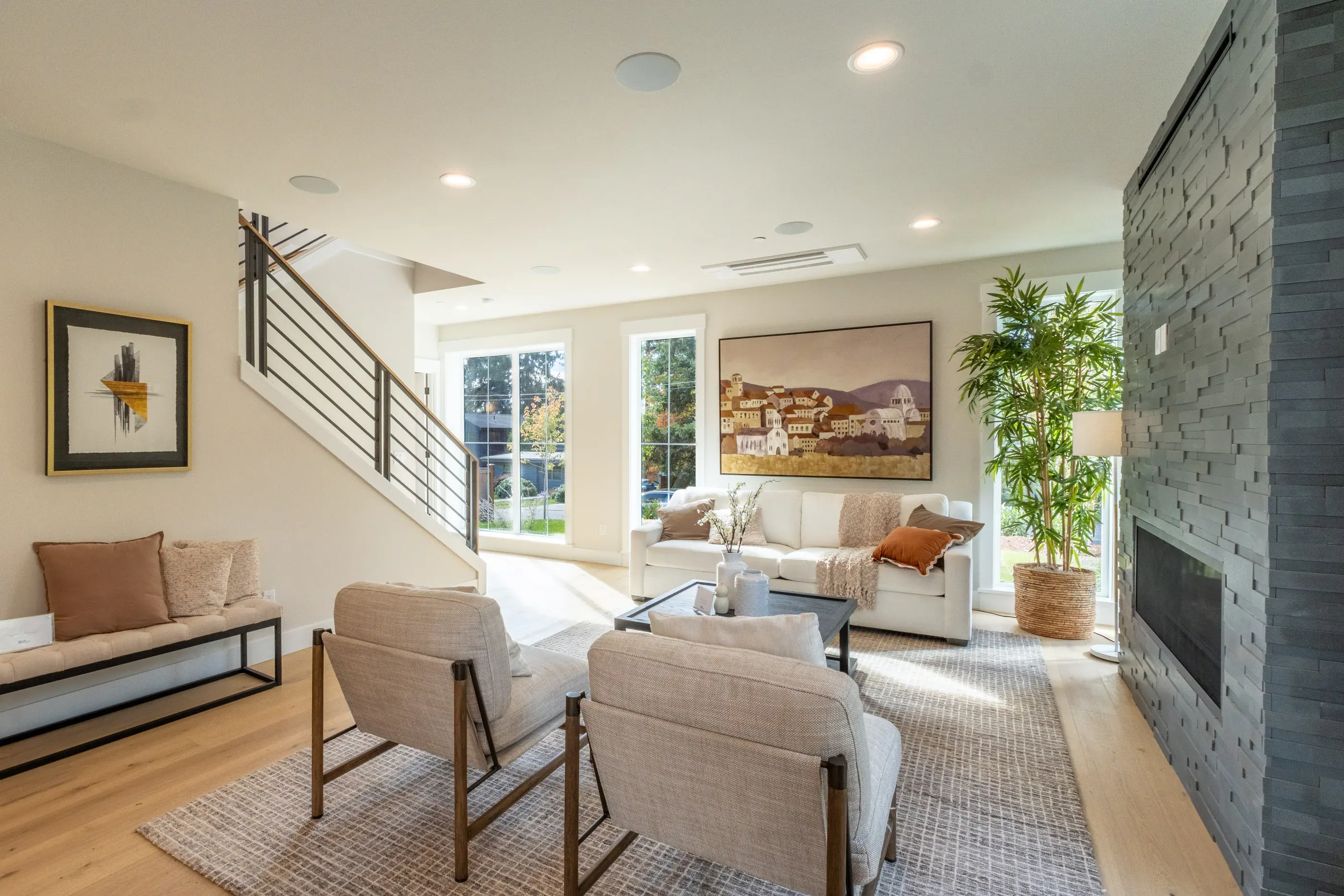 Living room with fireplace, staircase, and large windows.