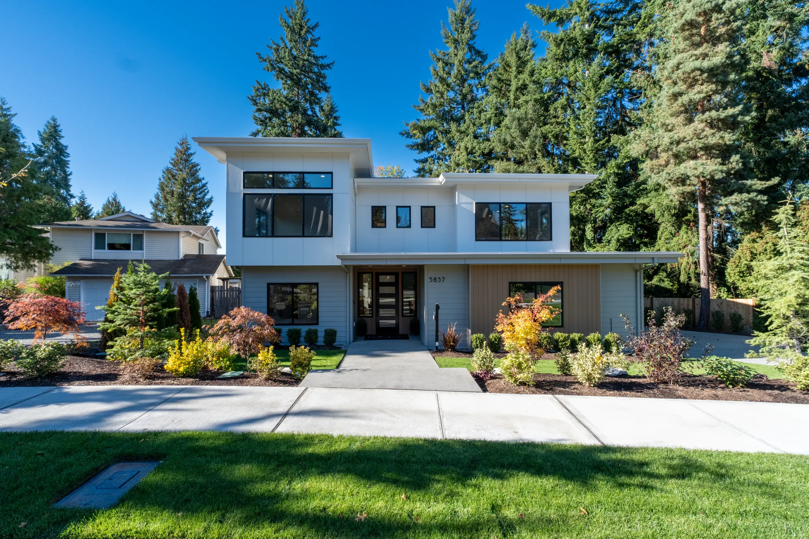 Modern home exterior with garden and large front windows.
