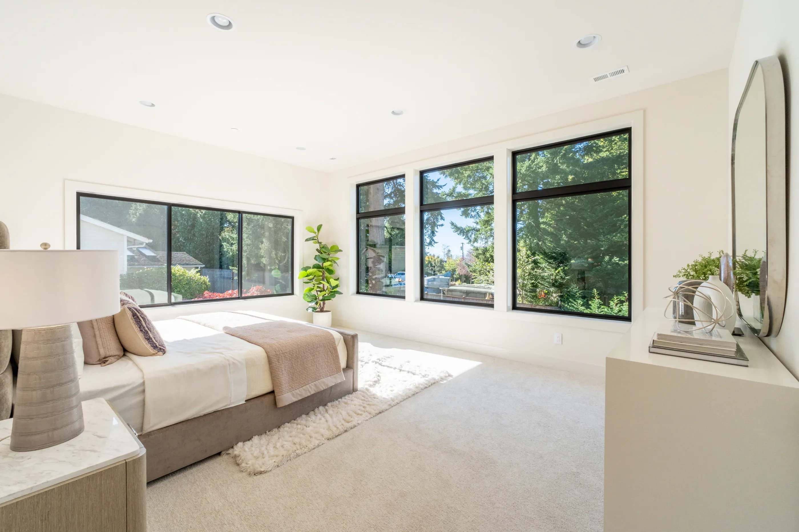 Bright bedroom with large windows and neutral bedding.