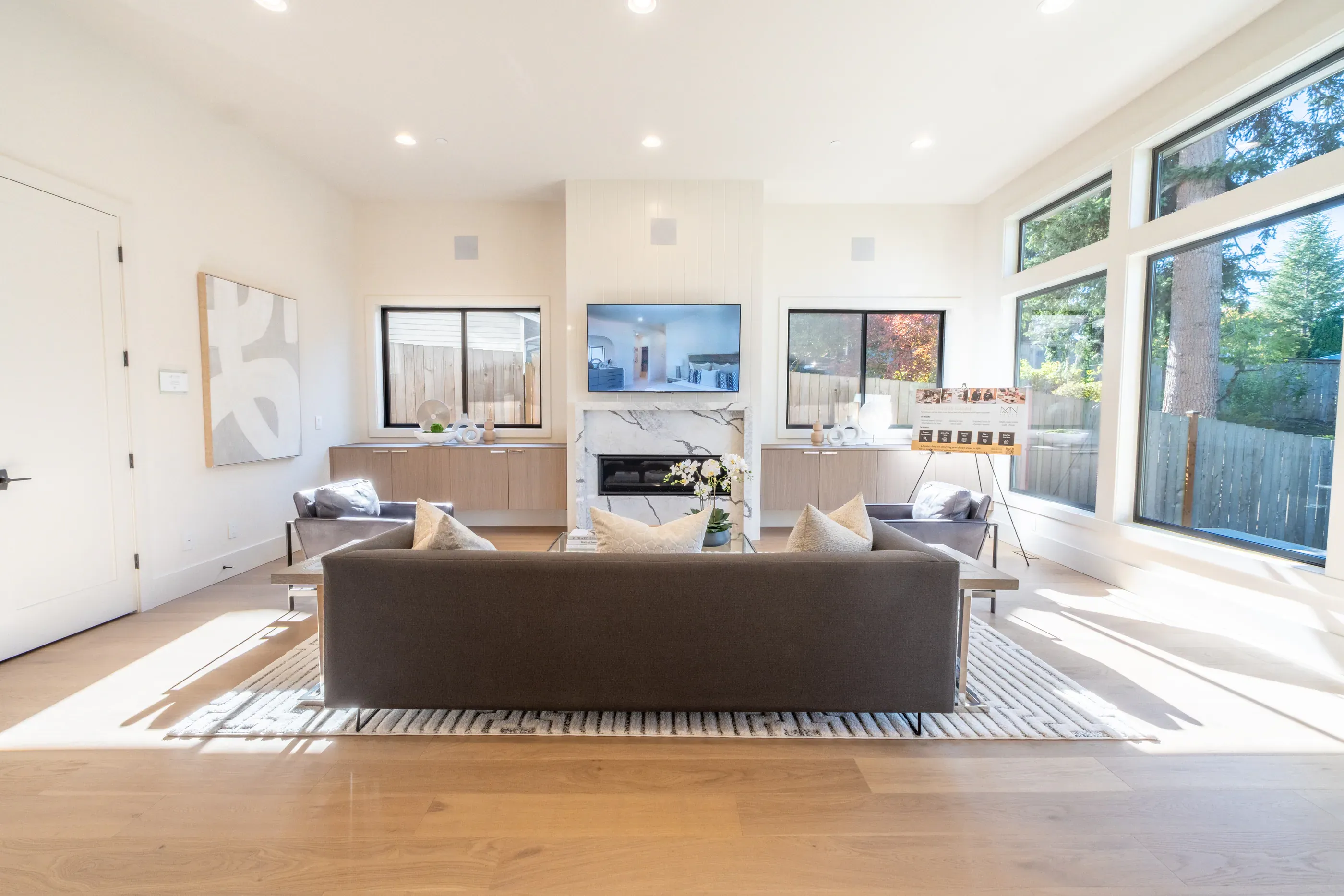 Open living room with sofa, fireplace, and large windows.