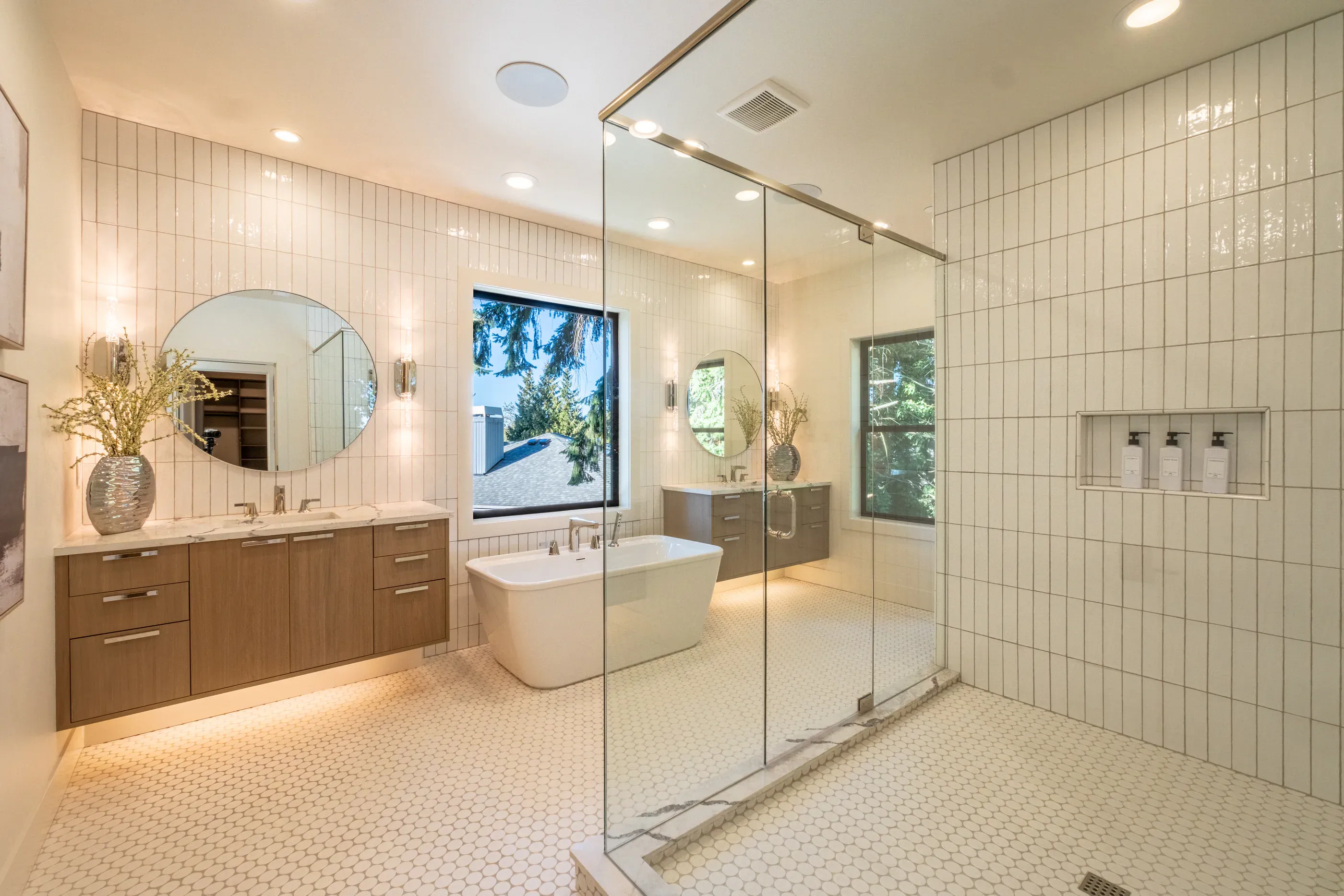 Bathroom with glass shower, bathtub, and double vanity.