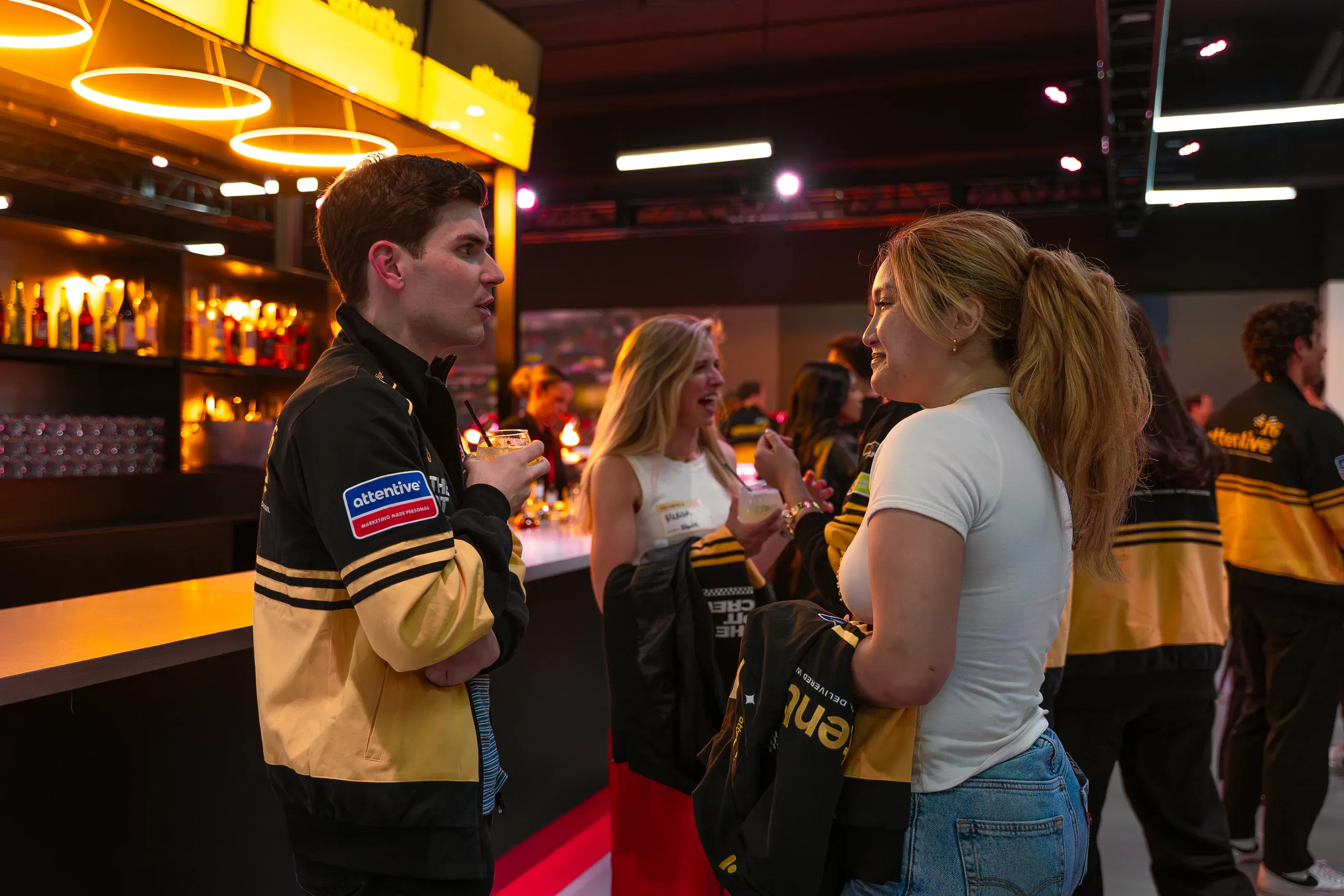 Two people talk beside an Attentive-branded event vehicle.