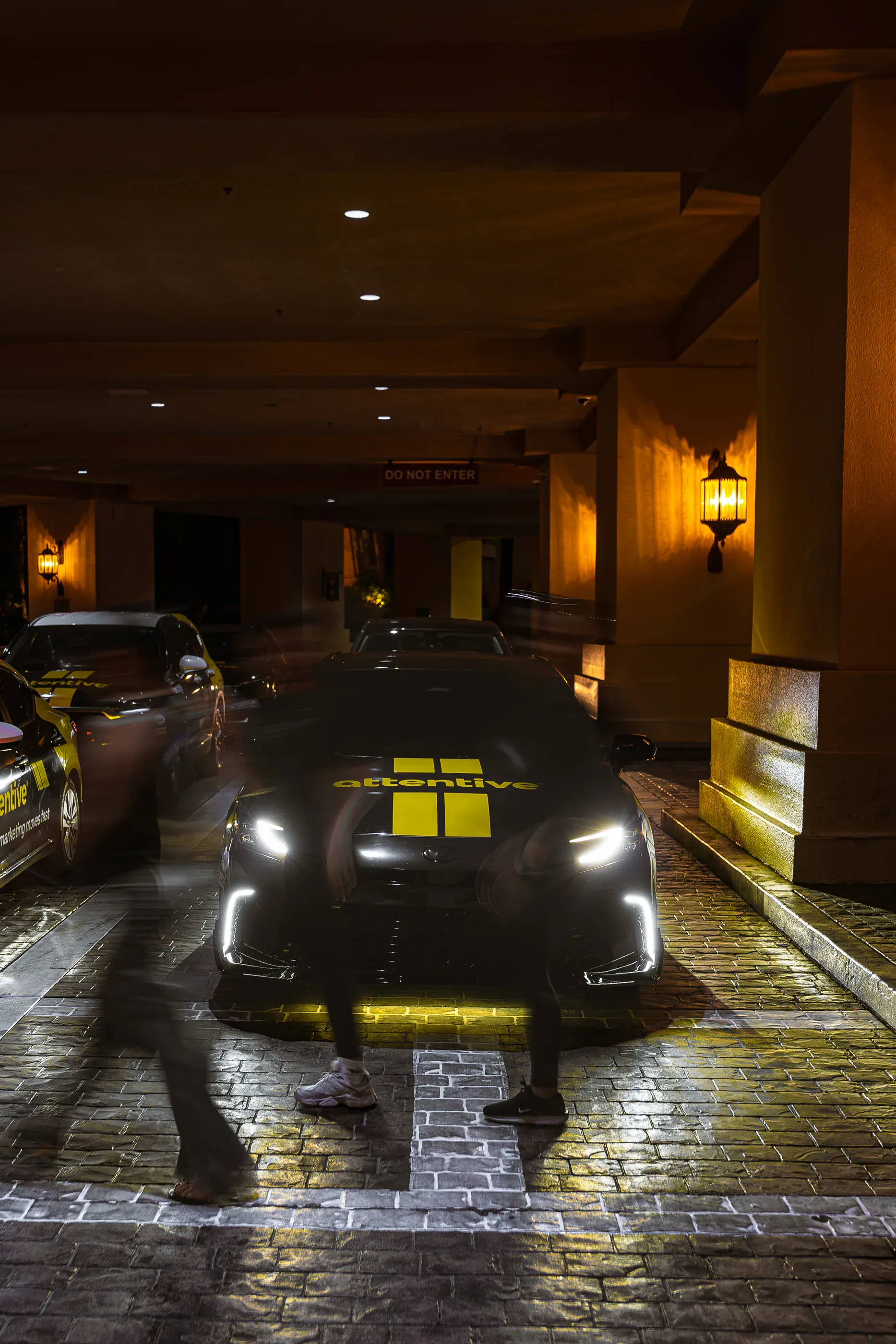 Attentive-branded car waits outside a hotel entrance at night.