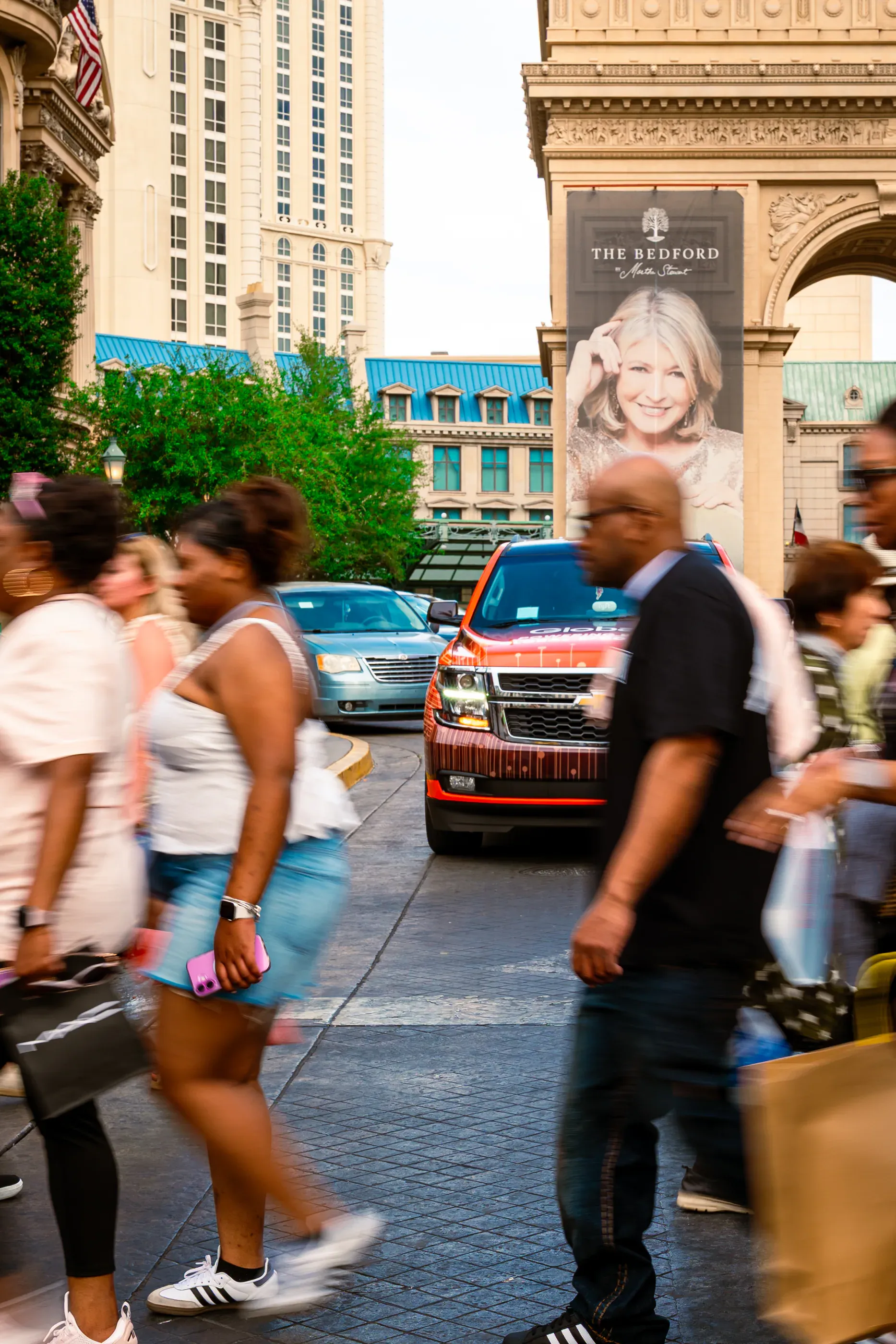 Pedestrians cross near a red Globale-branded vehicle.