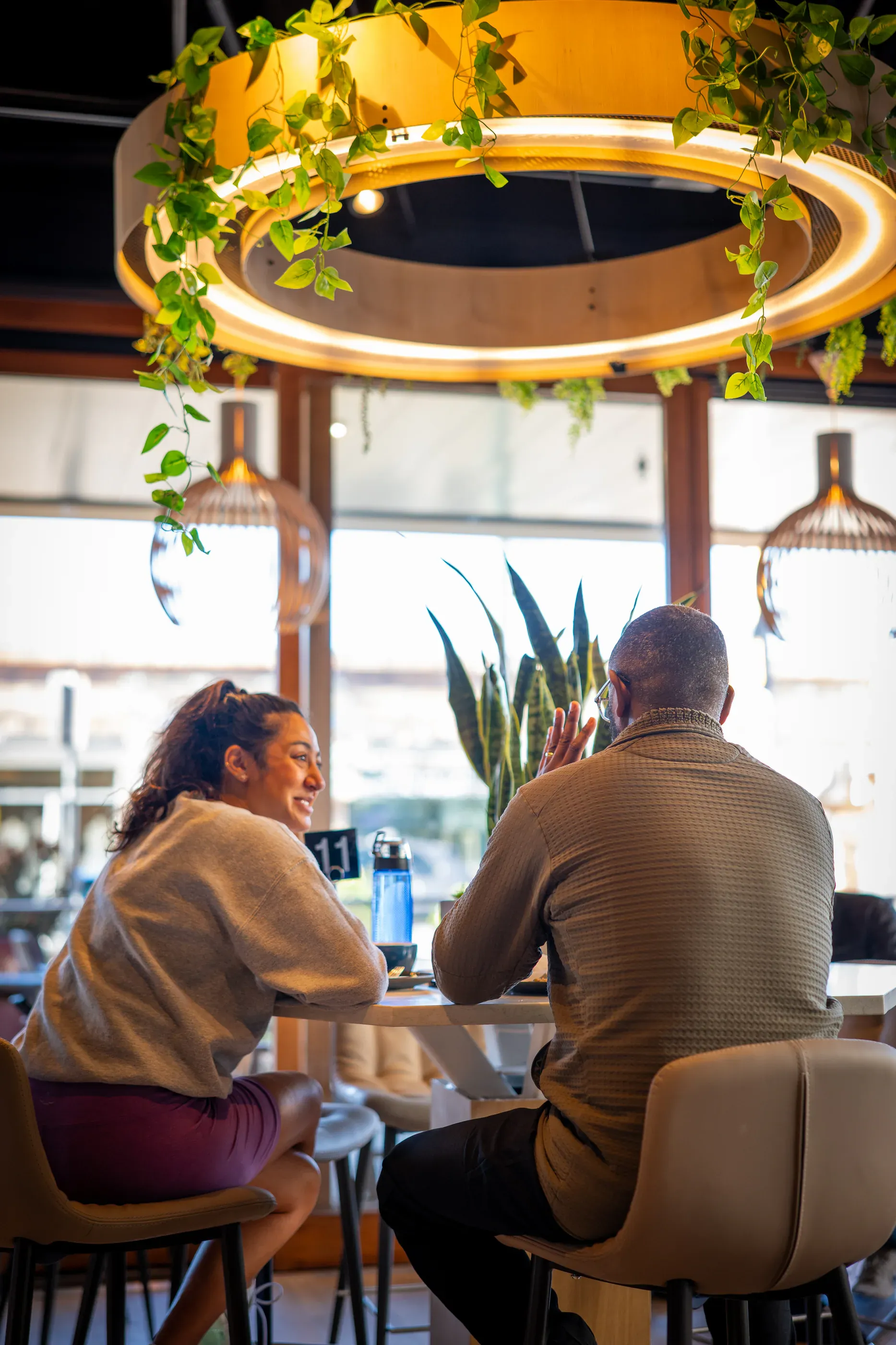 Cafe guests sit beneath circular ceiling lights.
