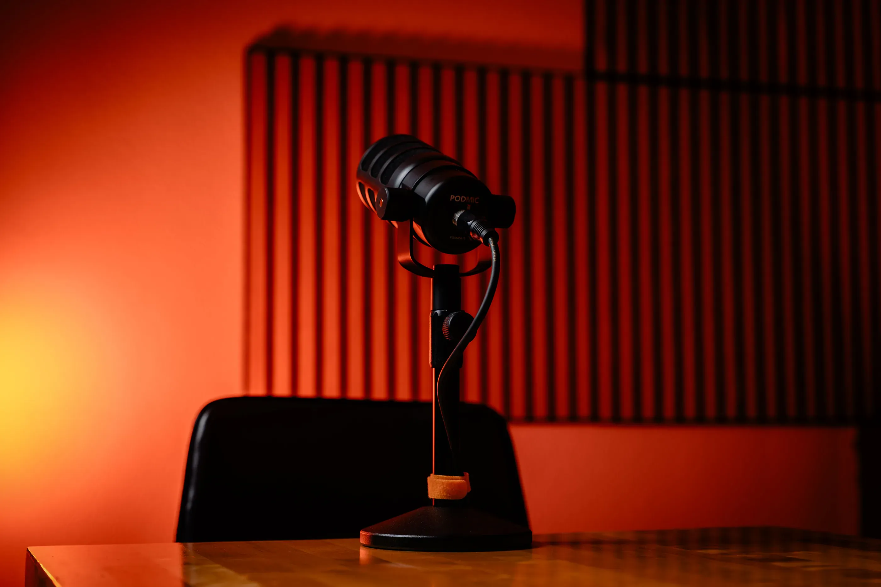 Podcast microphone on a desk with red studio lighting.