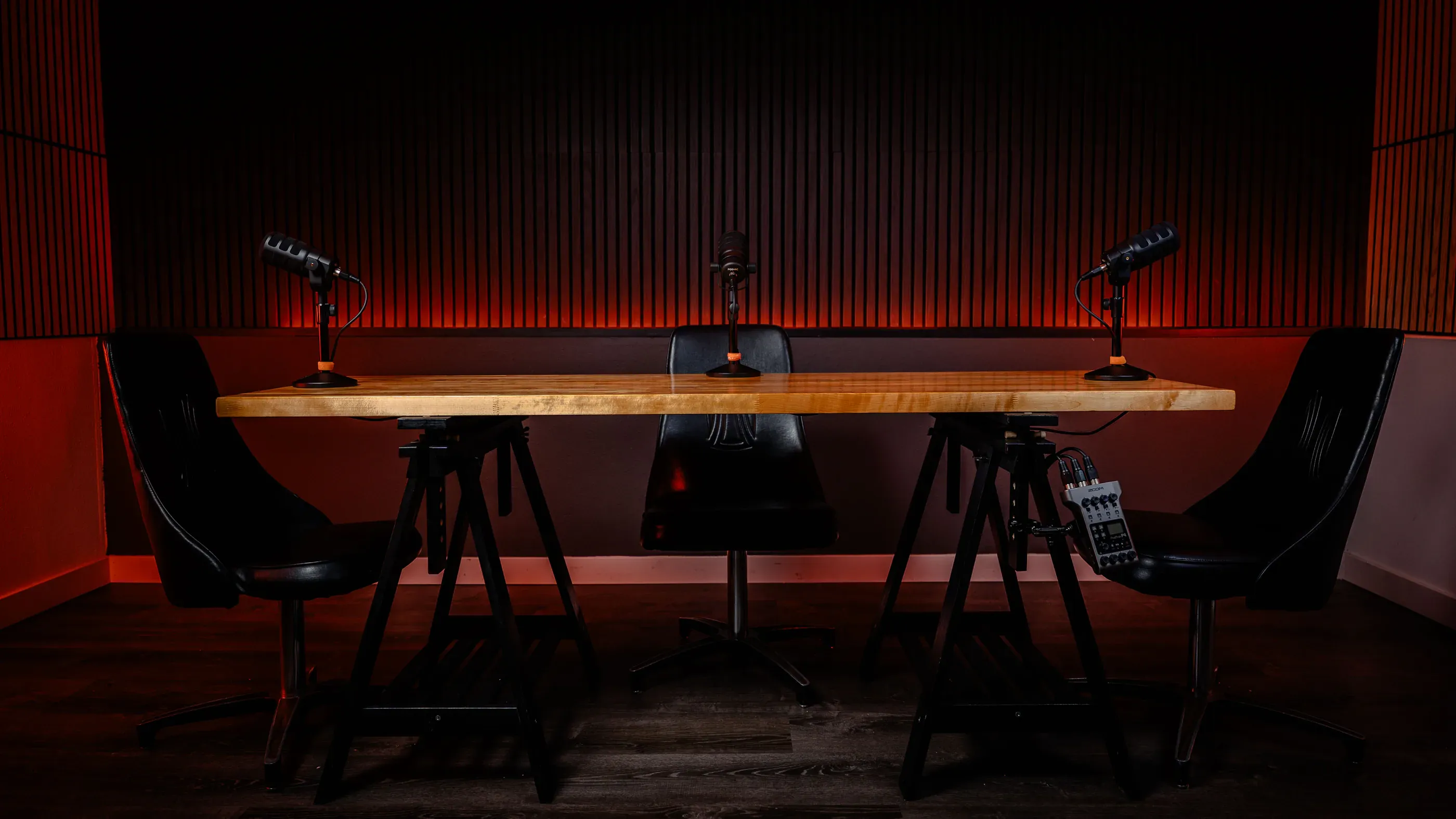 Podcast studio table set with microphones and chairs.