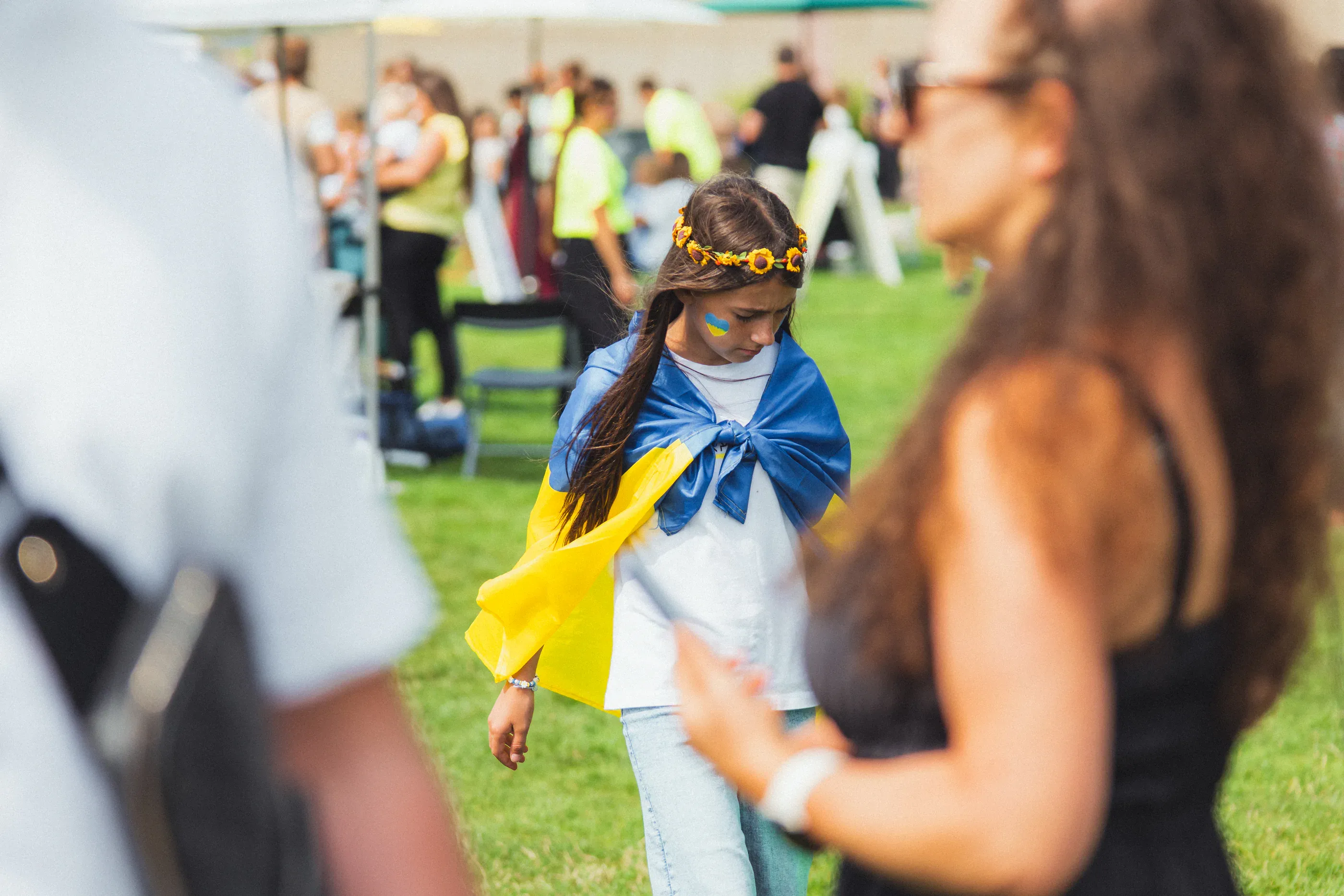 Child runs outdoors wearing a blue and yellow scarf.