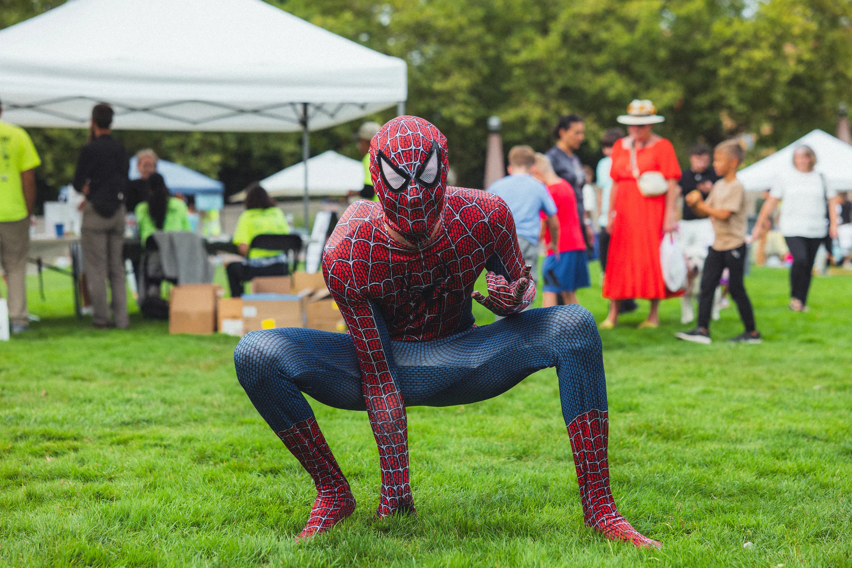 Costumed performer crouches on a grassy festival field.