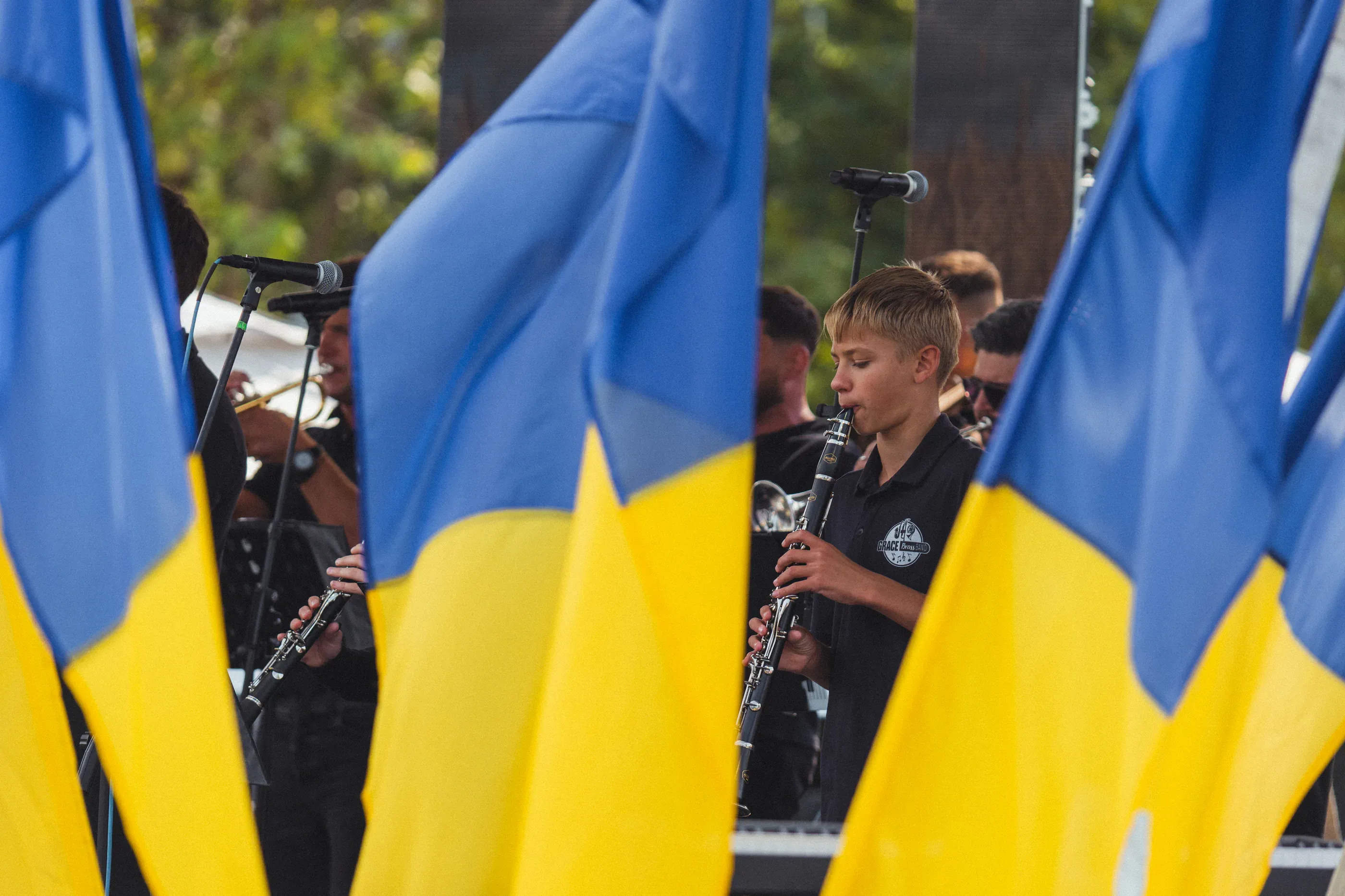 Ukrainian flags frame a singer at an outdoor festival.