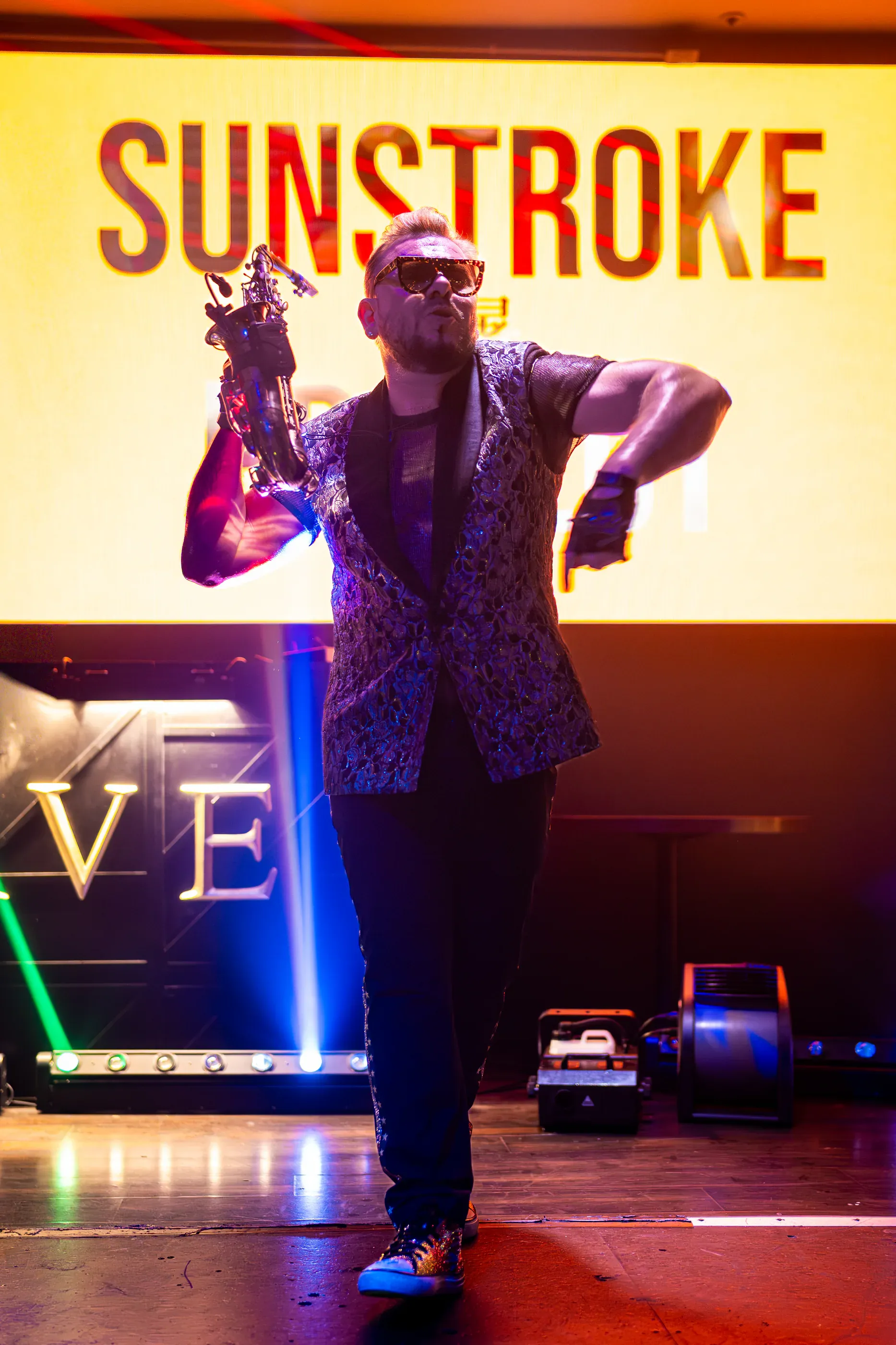 SunStroke Project performer sings in front of a bright screen.