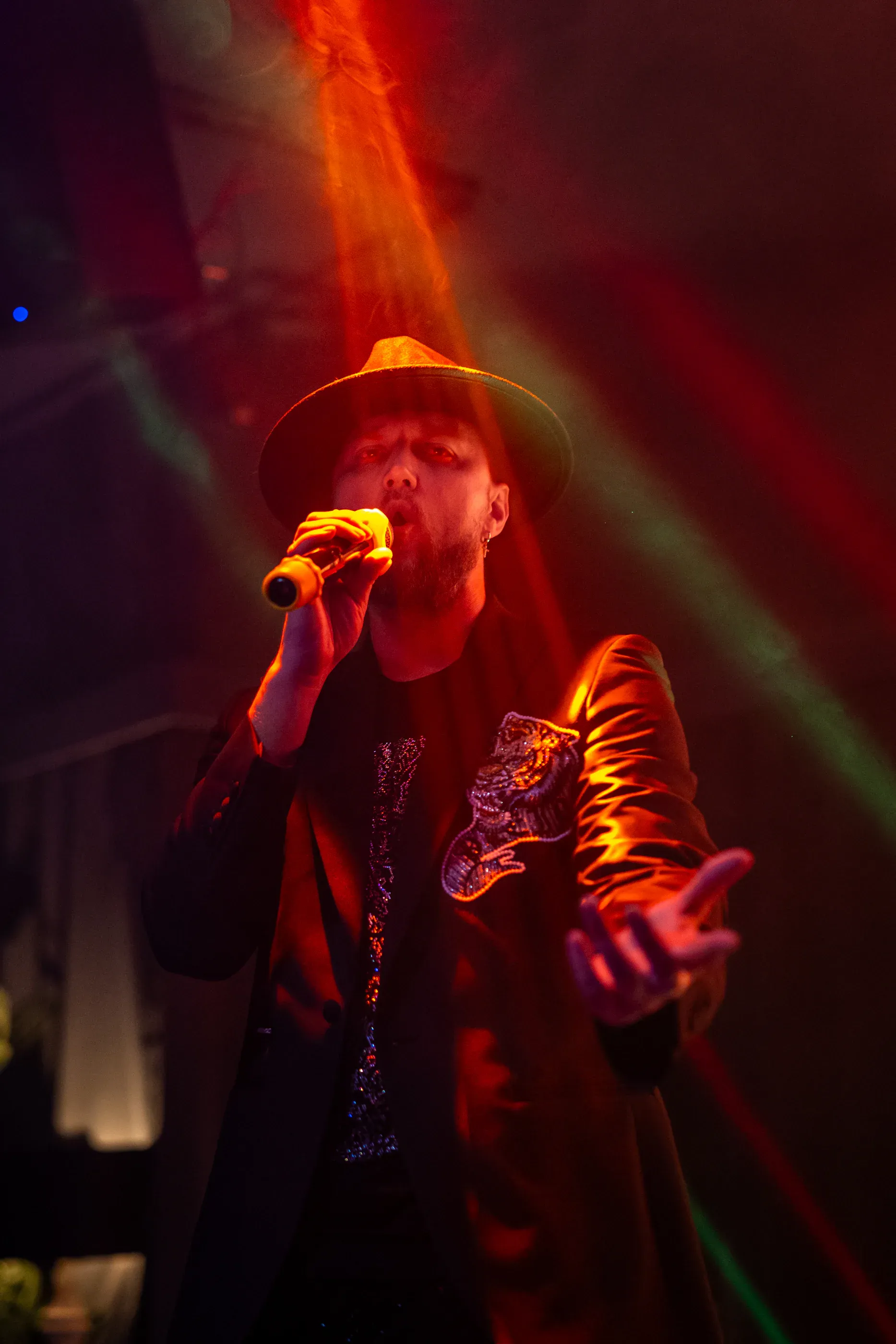 Singer performs under red and green stage lights.