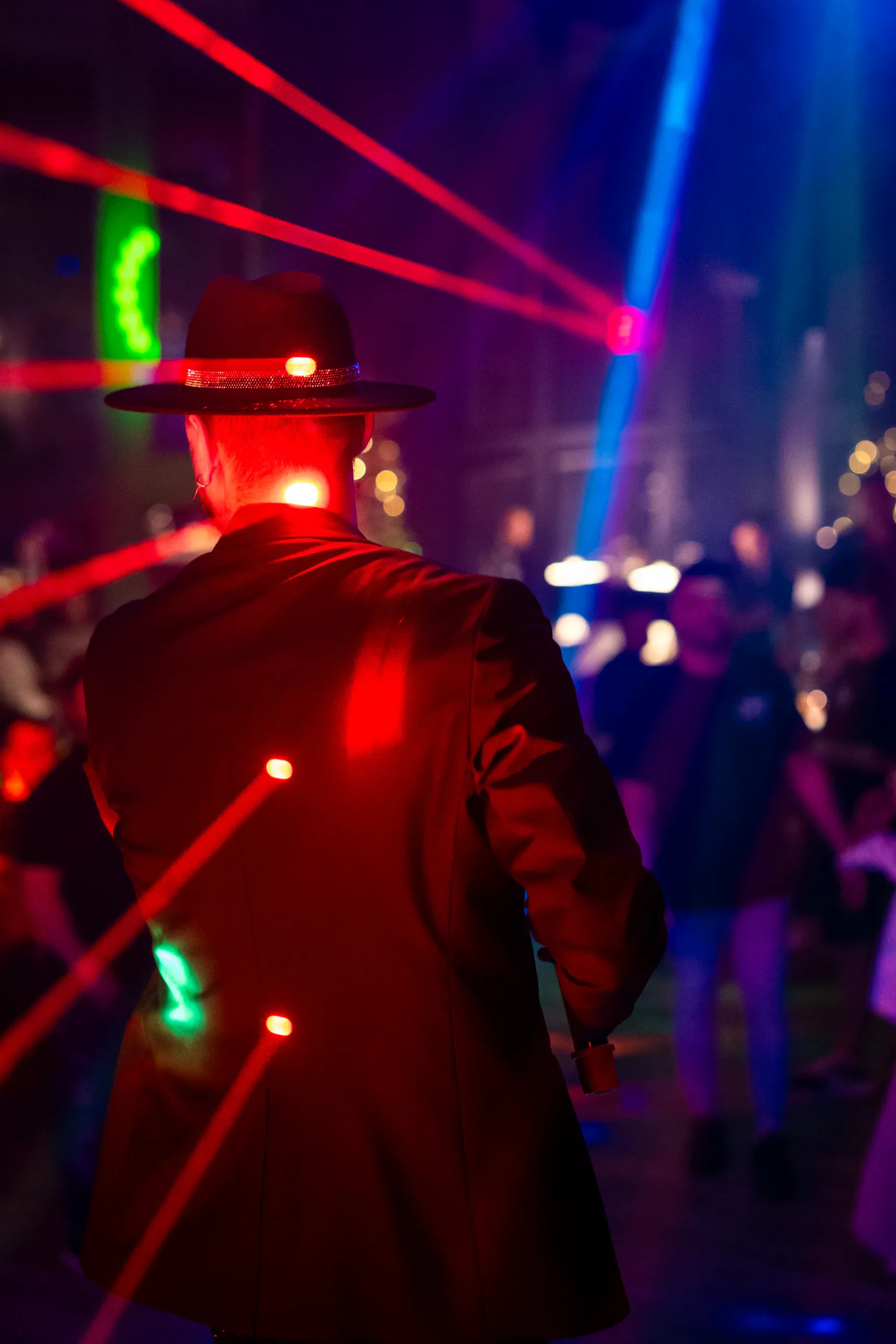 Audience member faces colorful laser lights during a concert.
