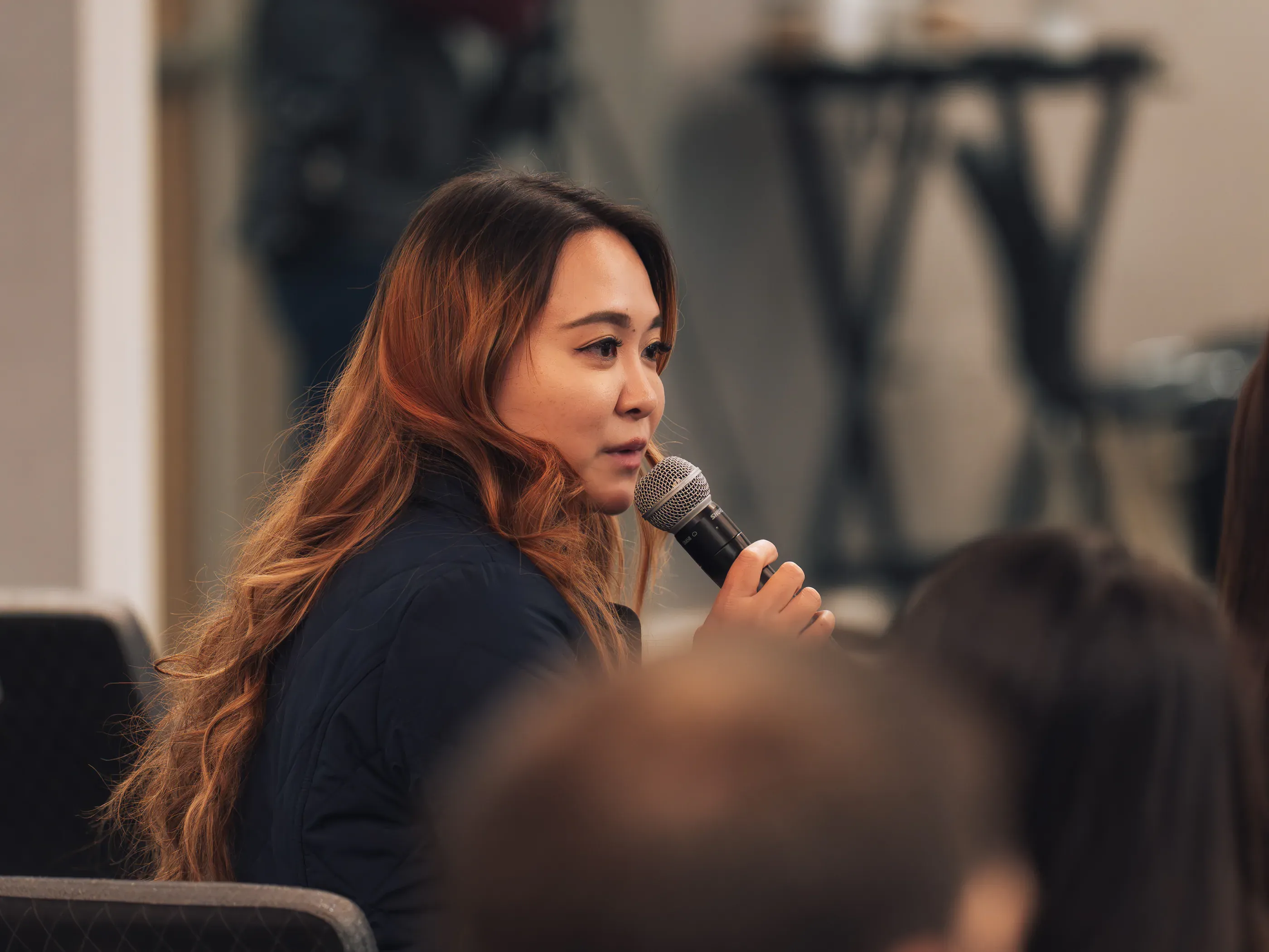 An attendee asking a question with a handheld microphone during a summit session.