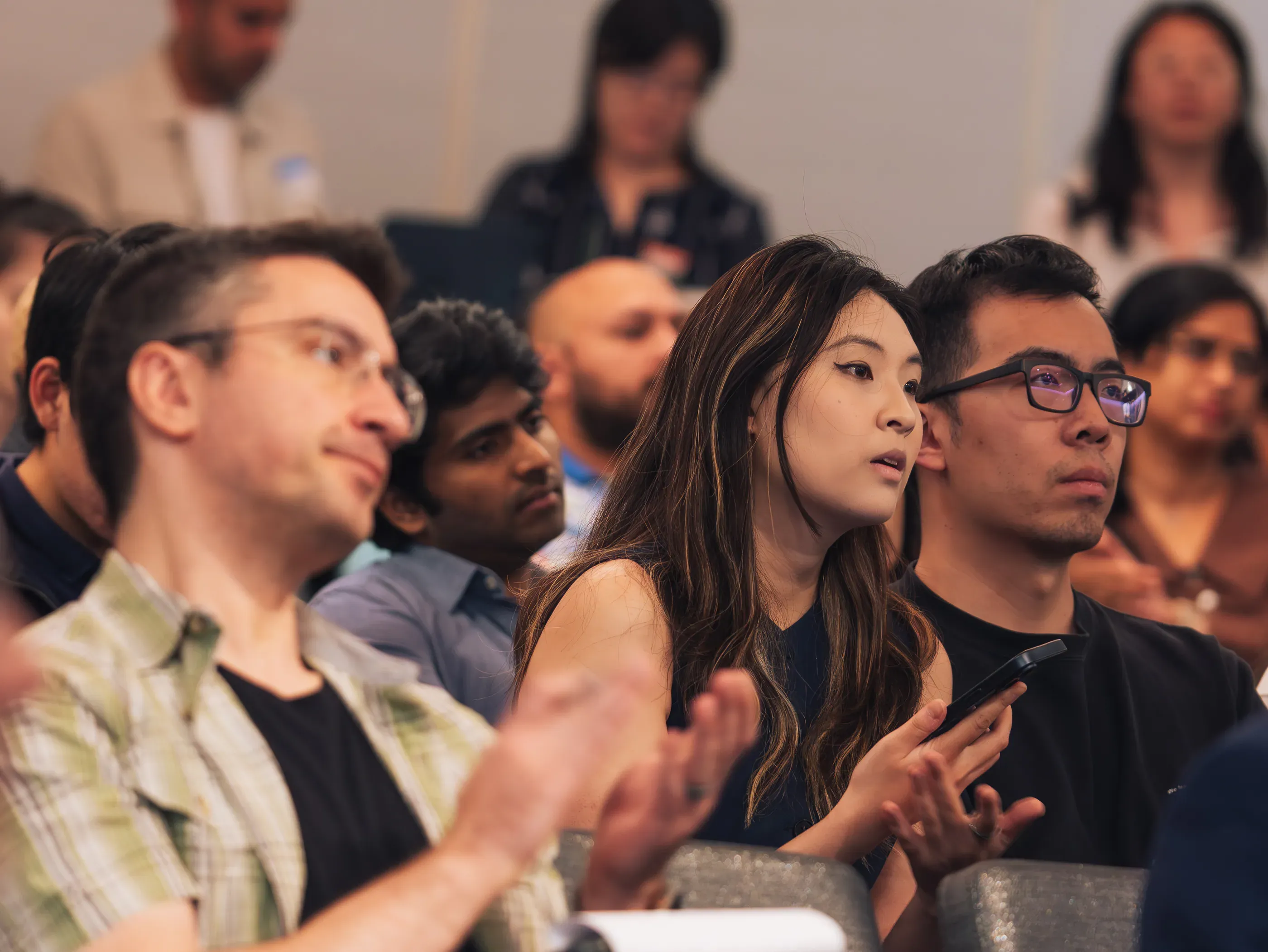 Audience members applauding in the front rows during a talk at the Seattle AI Summit.