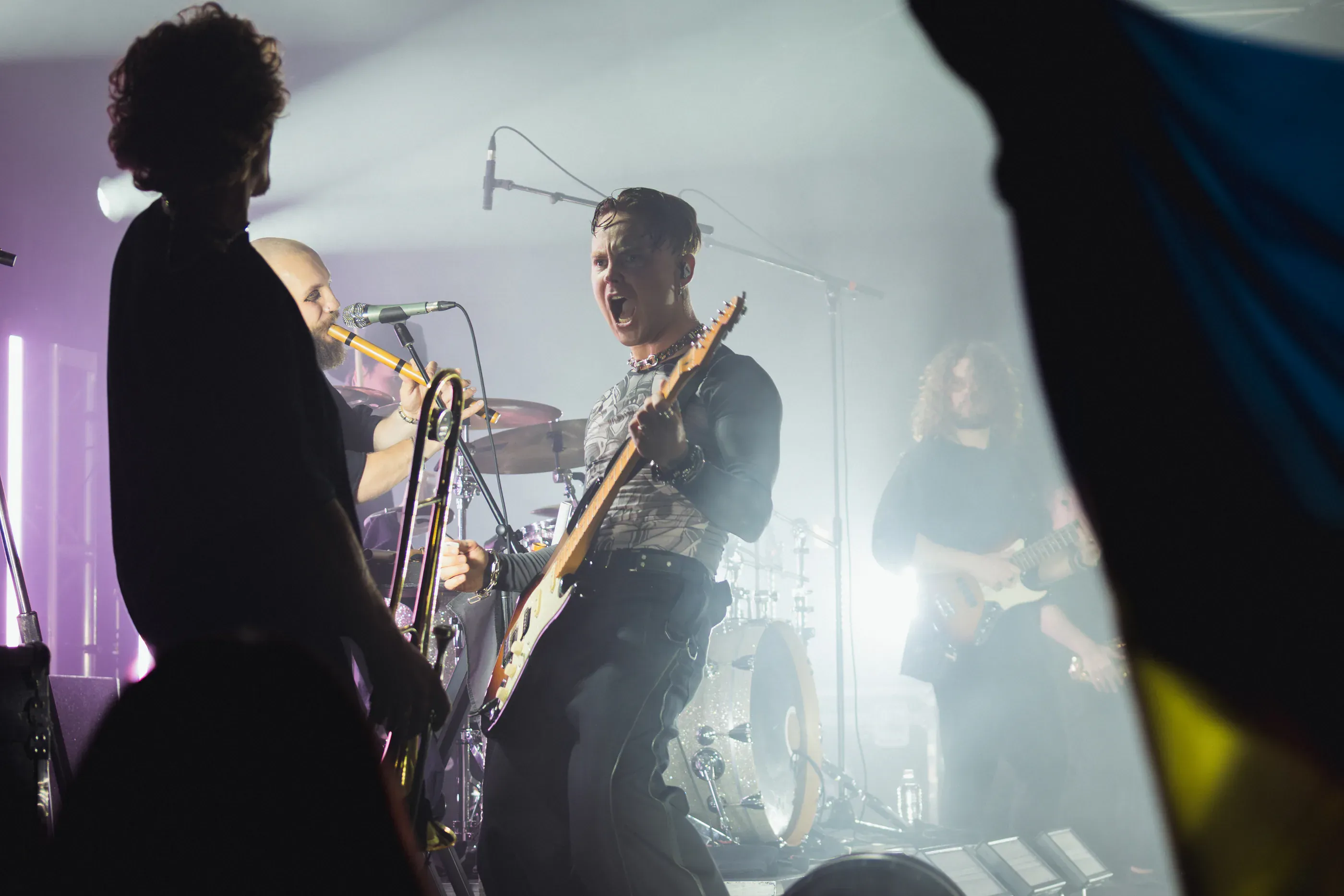 Band members perform under white stage lights.