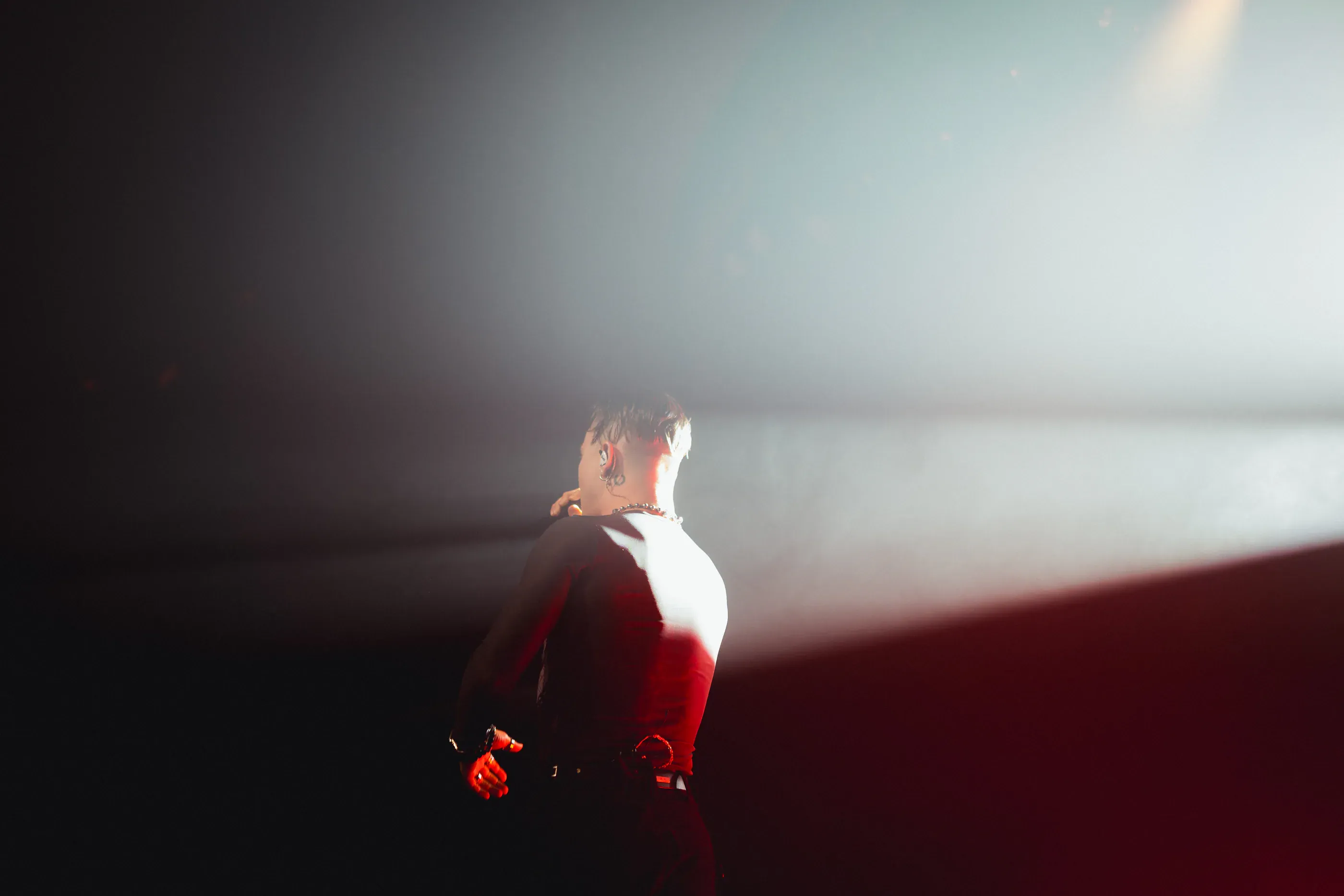 Singer stands in a narrow beam of stage light.
