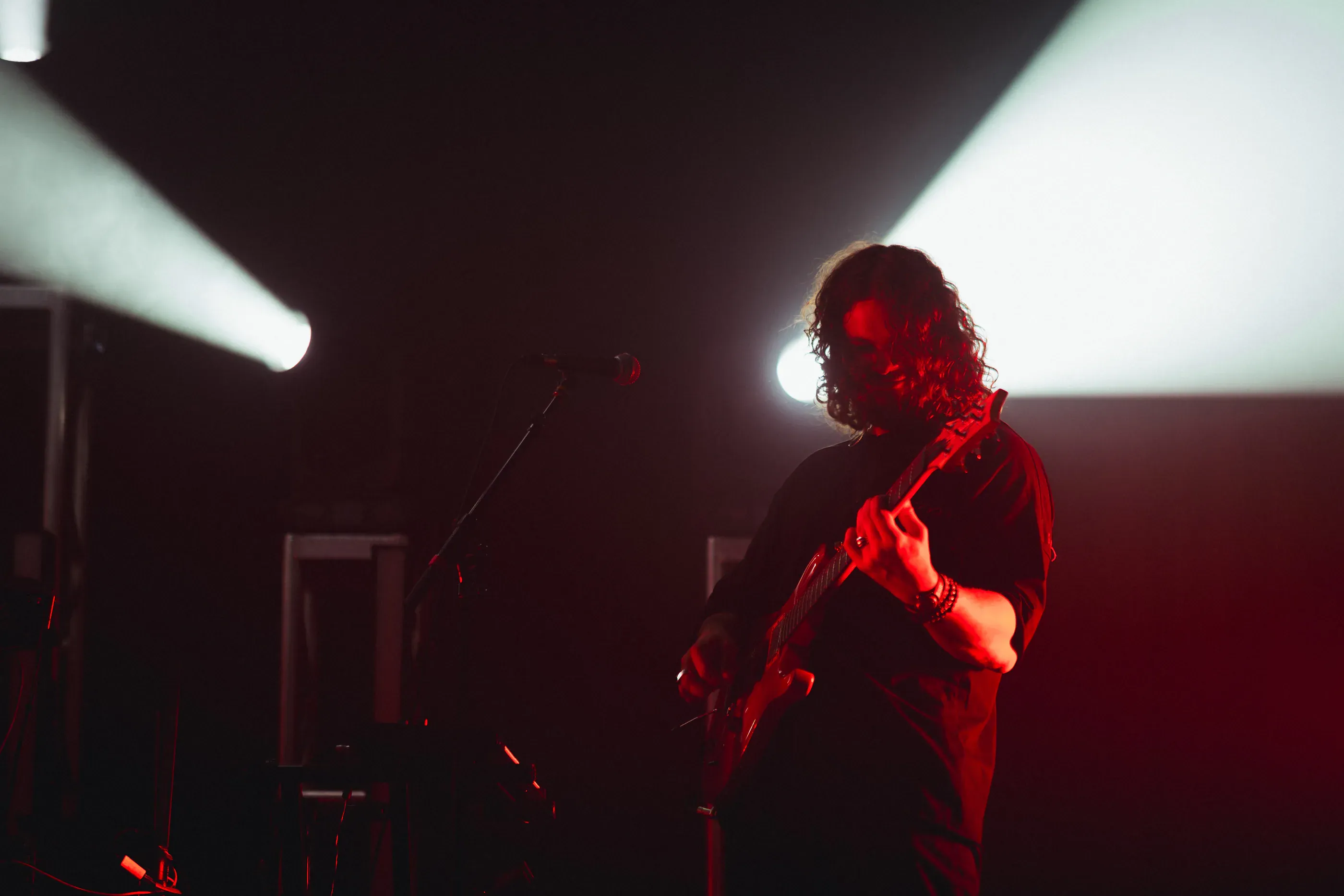 Guitarist performs in red and white stage light.