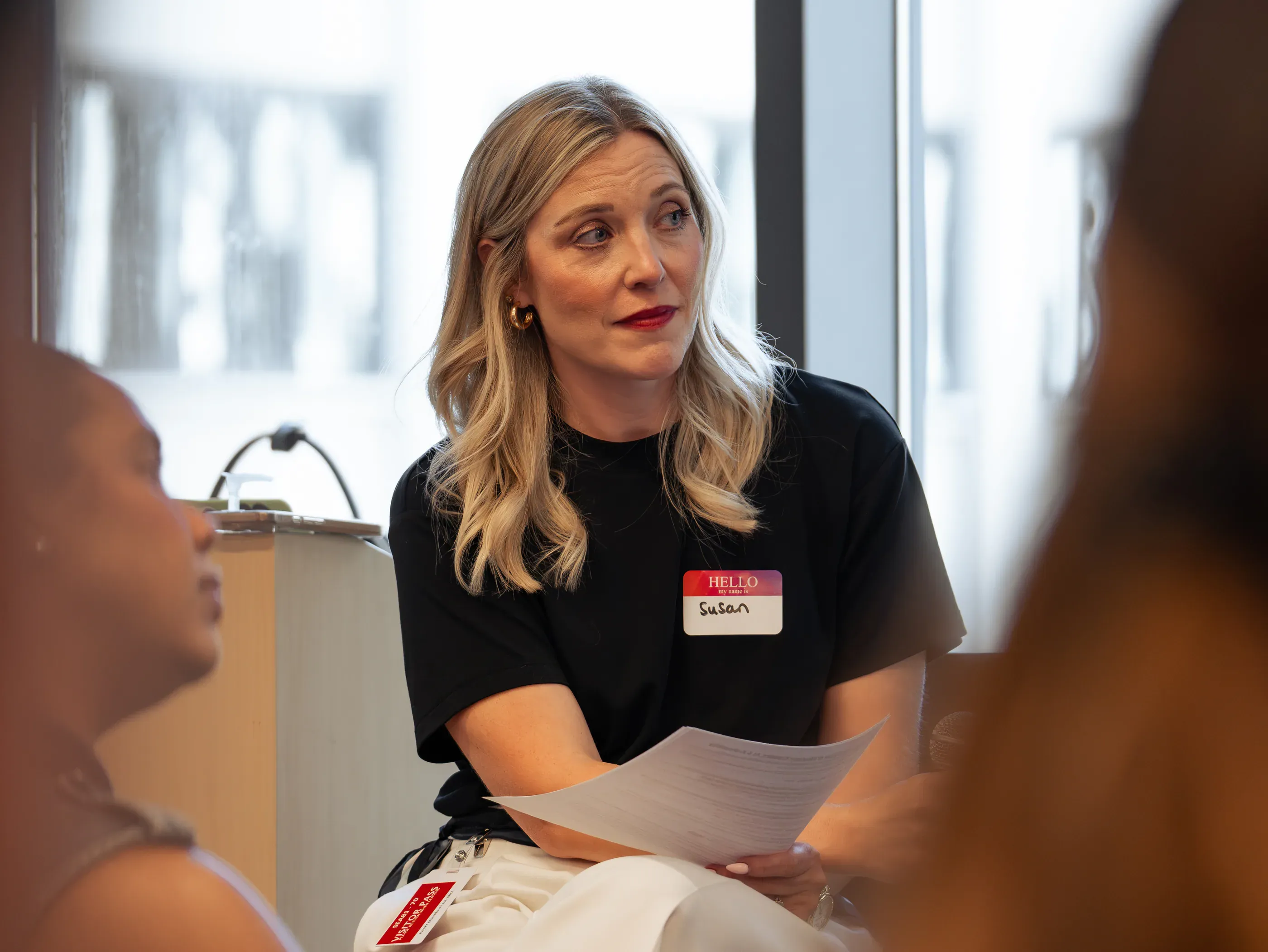 A participant with a name badge and printed notes talking during a small-group session.