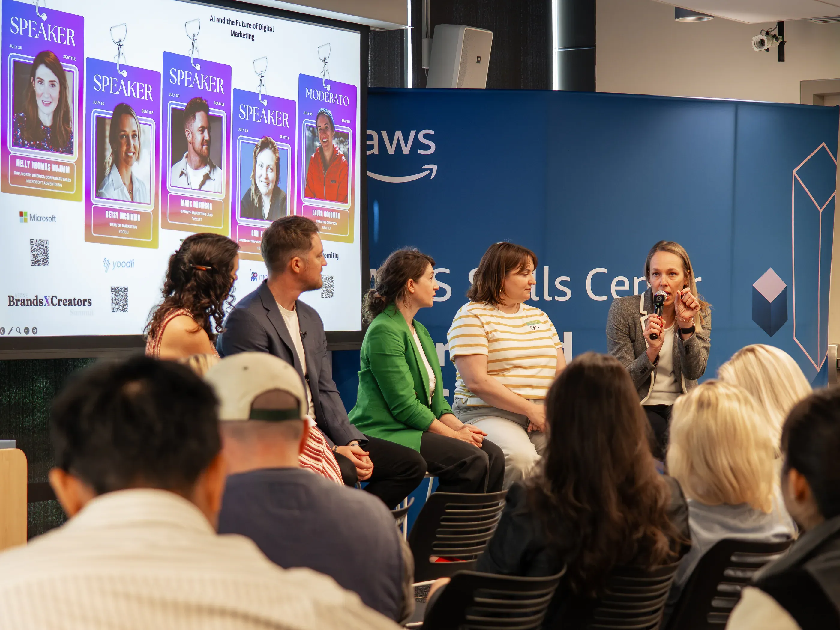 A five-person panel on AI and the future of digital marketing in front of the speaker lineup screen.