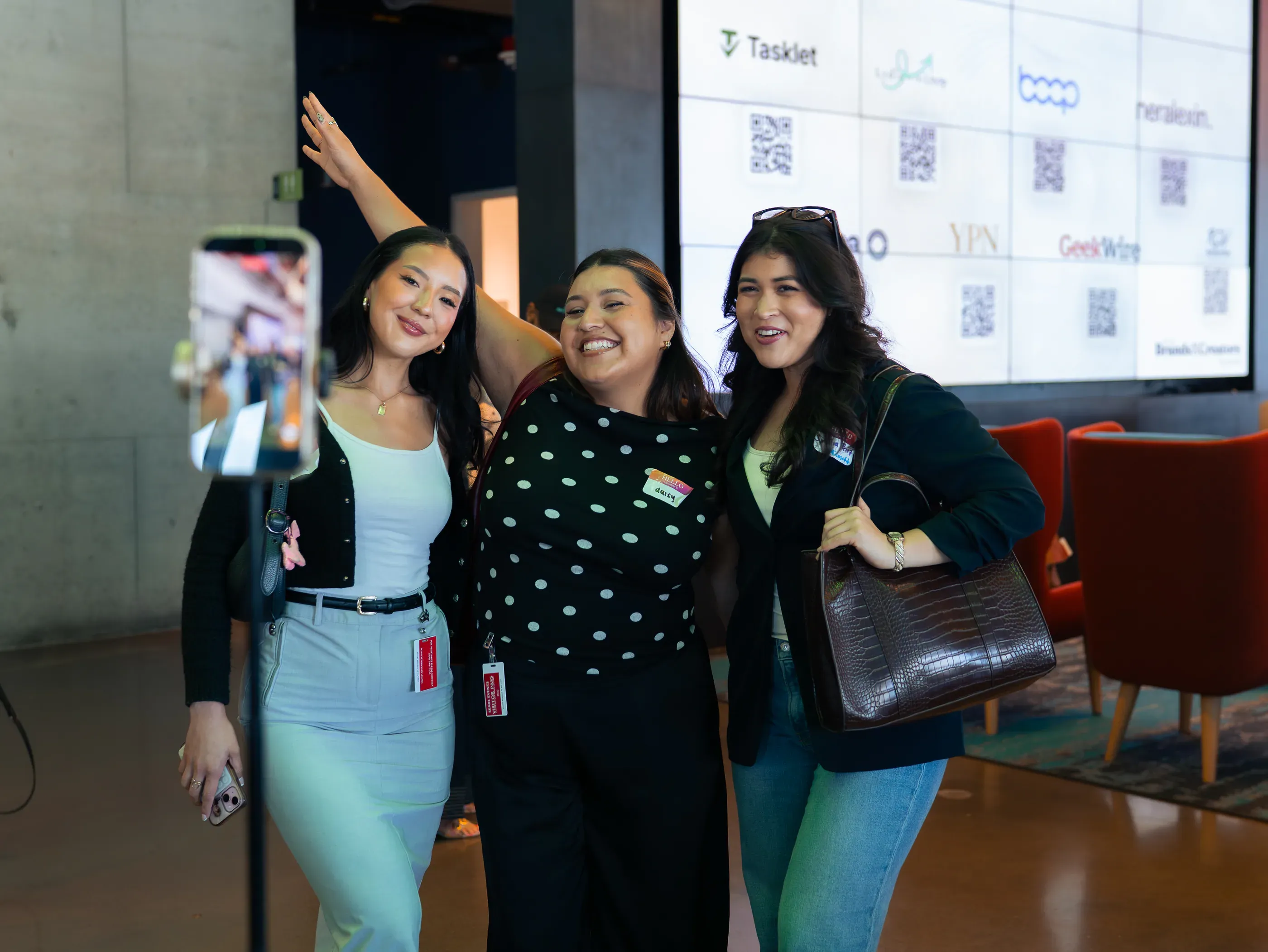 Three attendees posing together for a photo in front of the summit partner screen.