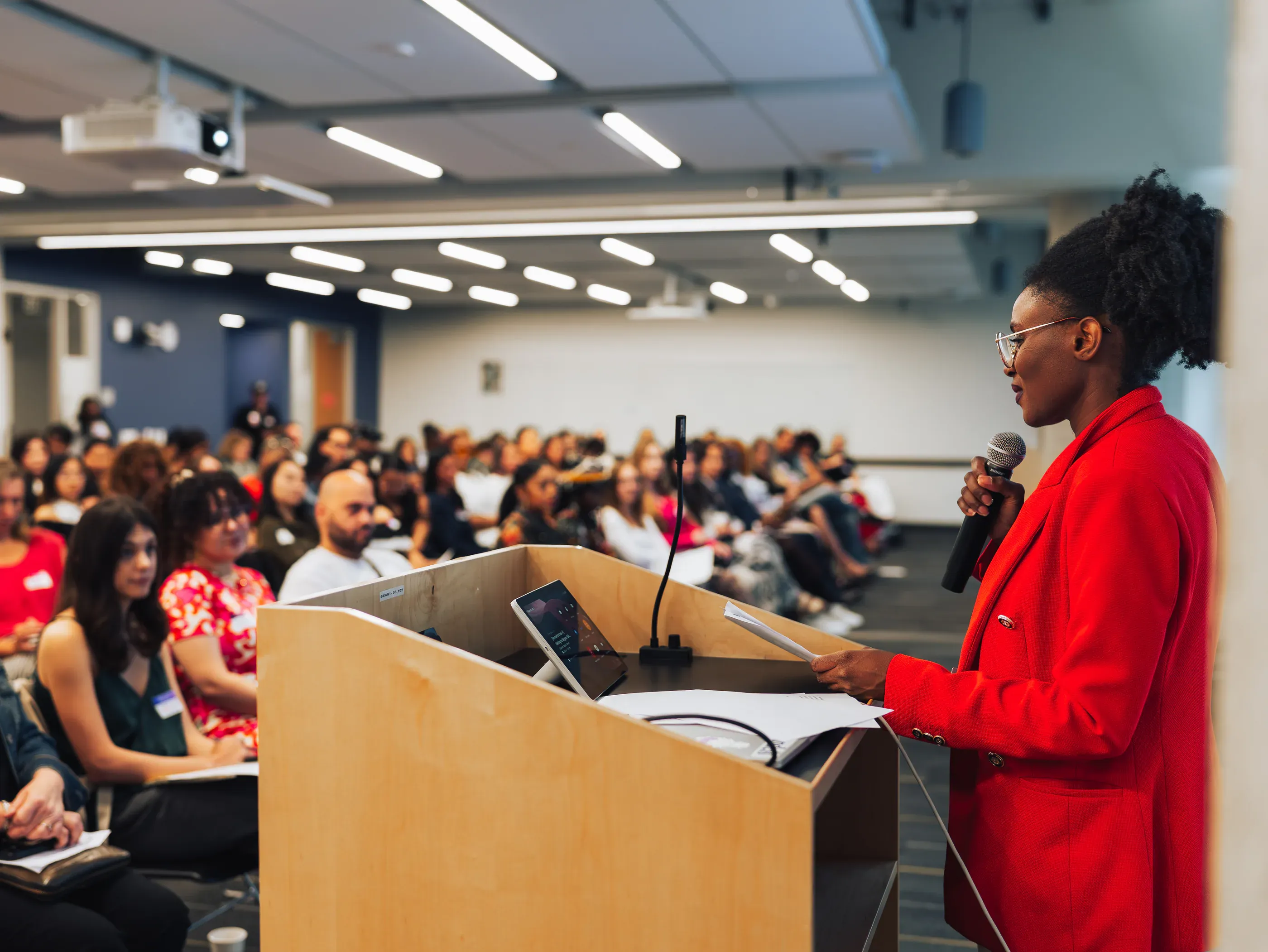 A speaker addressing a full room from the podium during the summit keynote.