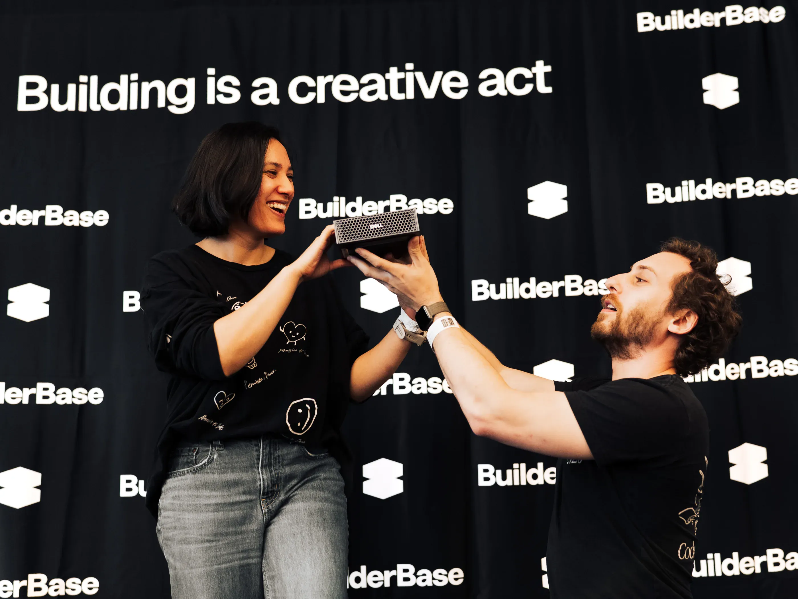 Two participants holding up a prize workstation together at the hackathon backdrop.