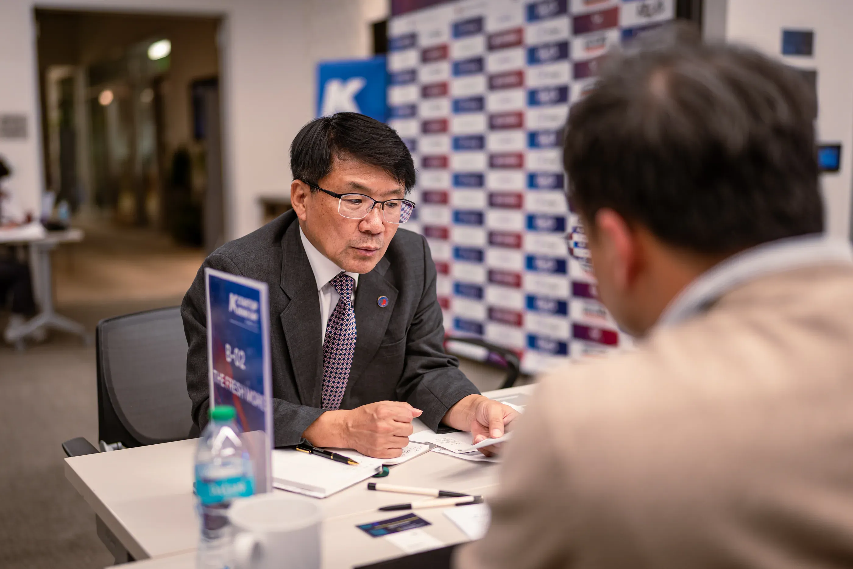 Startup founder speaks with an attendee at a meeting table.