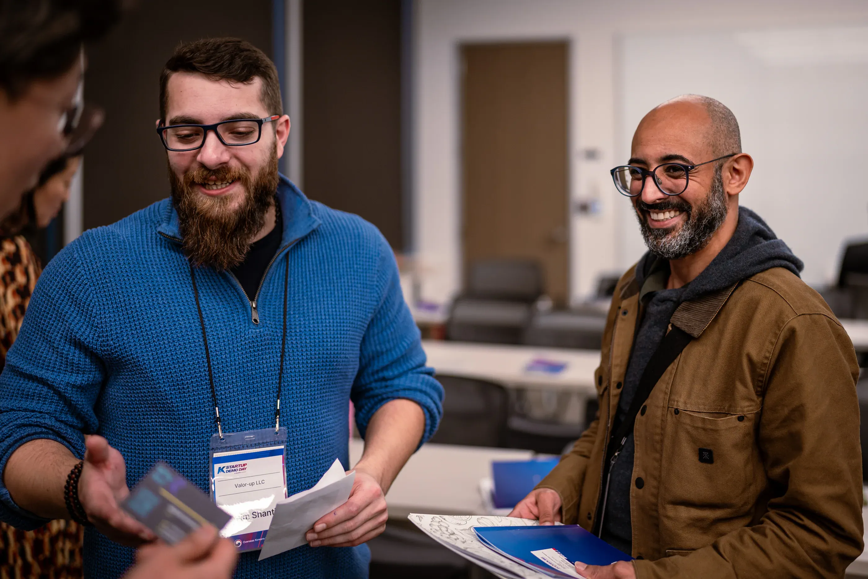 Two attendees talk and exchange cards at a startup event.