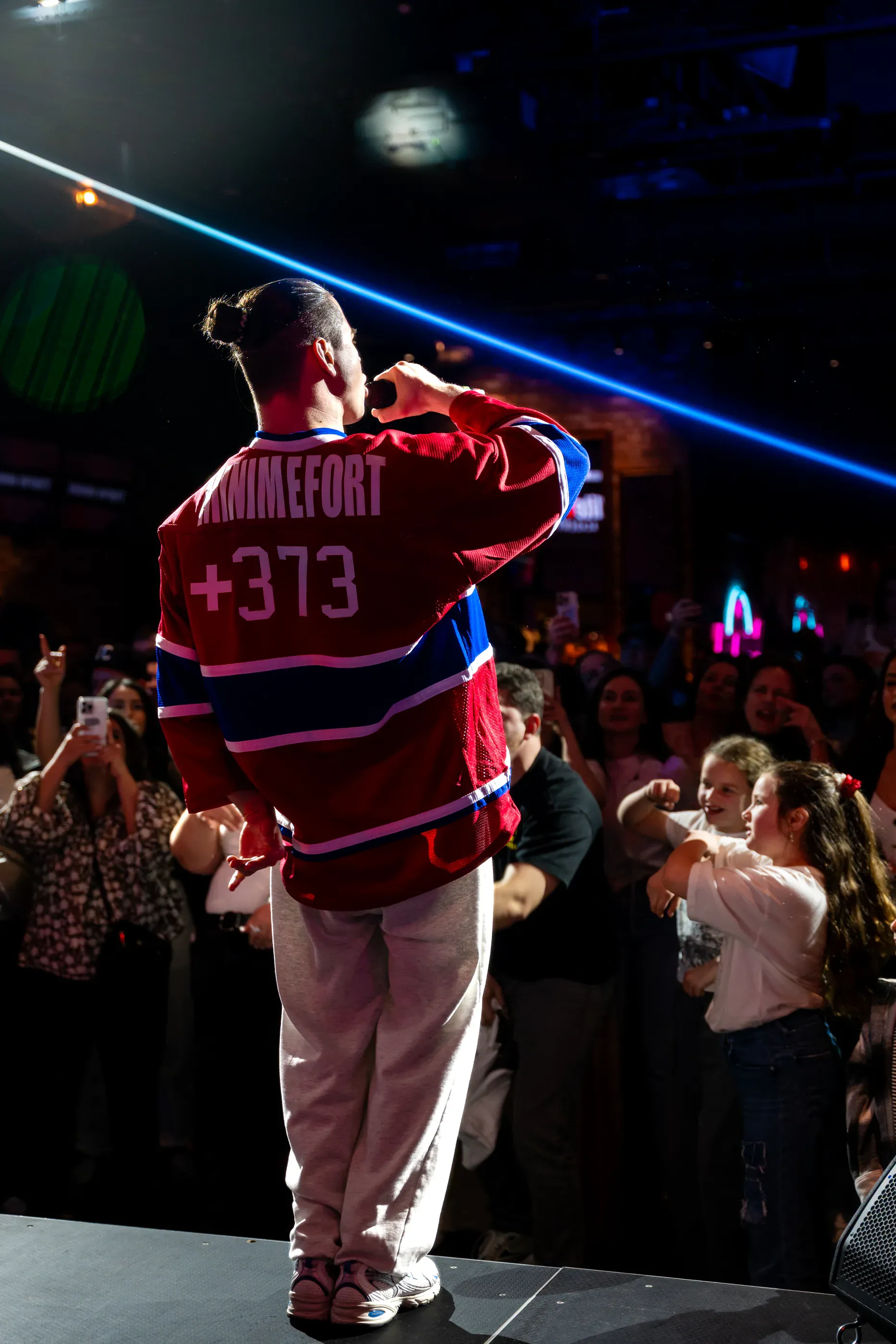 Performer in a red jersey faces the crowd on stage.