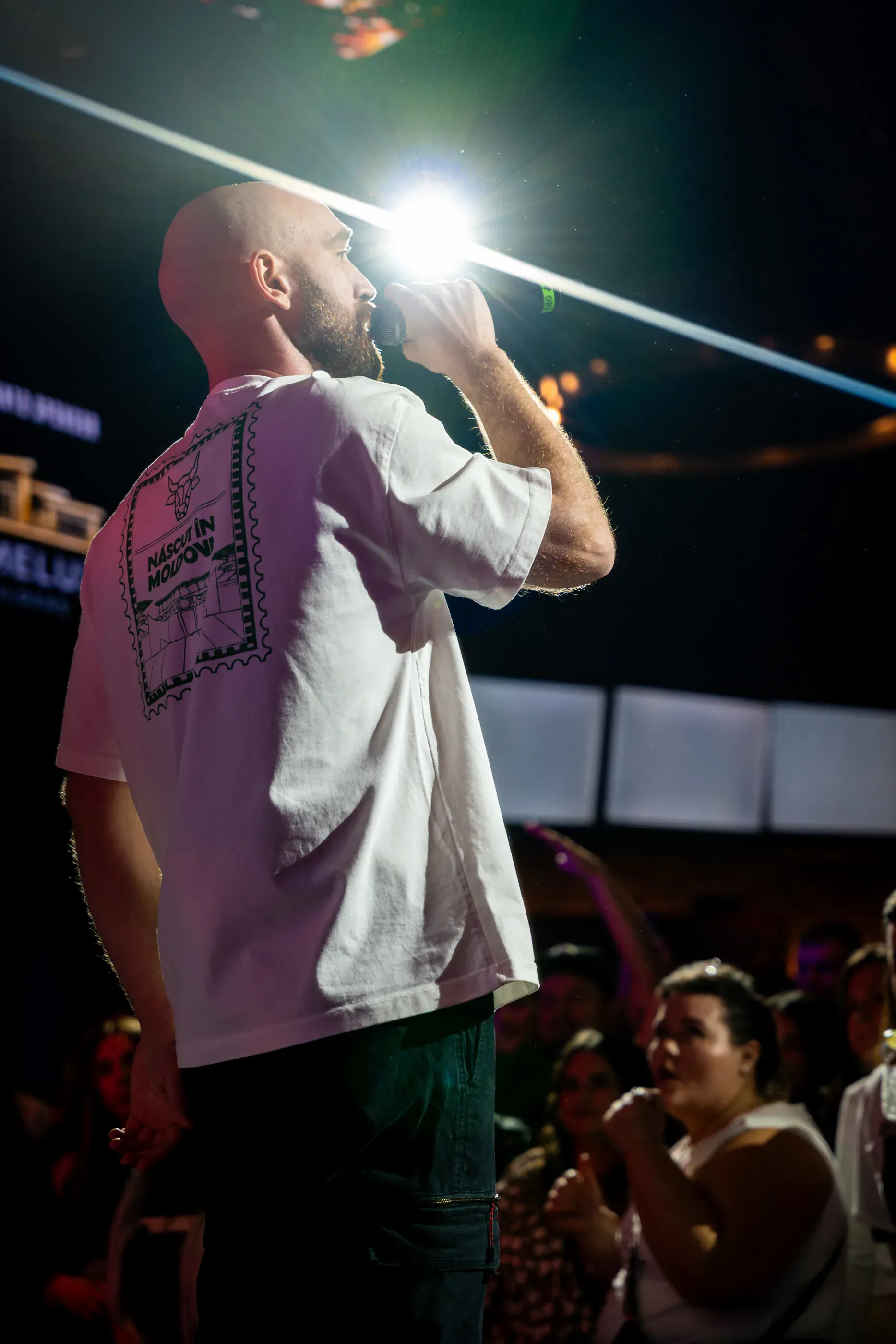 Singer performs into a handheld microphone under bright light.