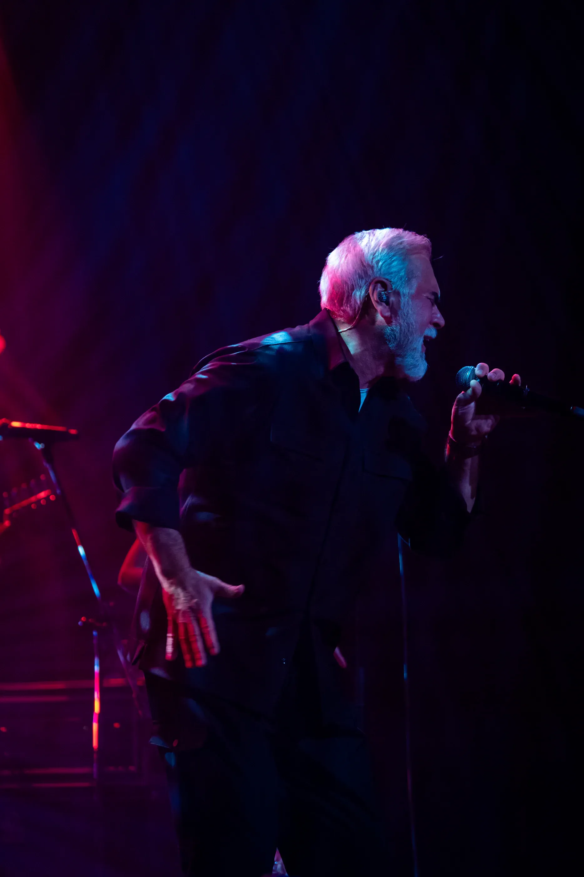 Valery Meladze sings under dark blue stage light.