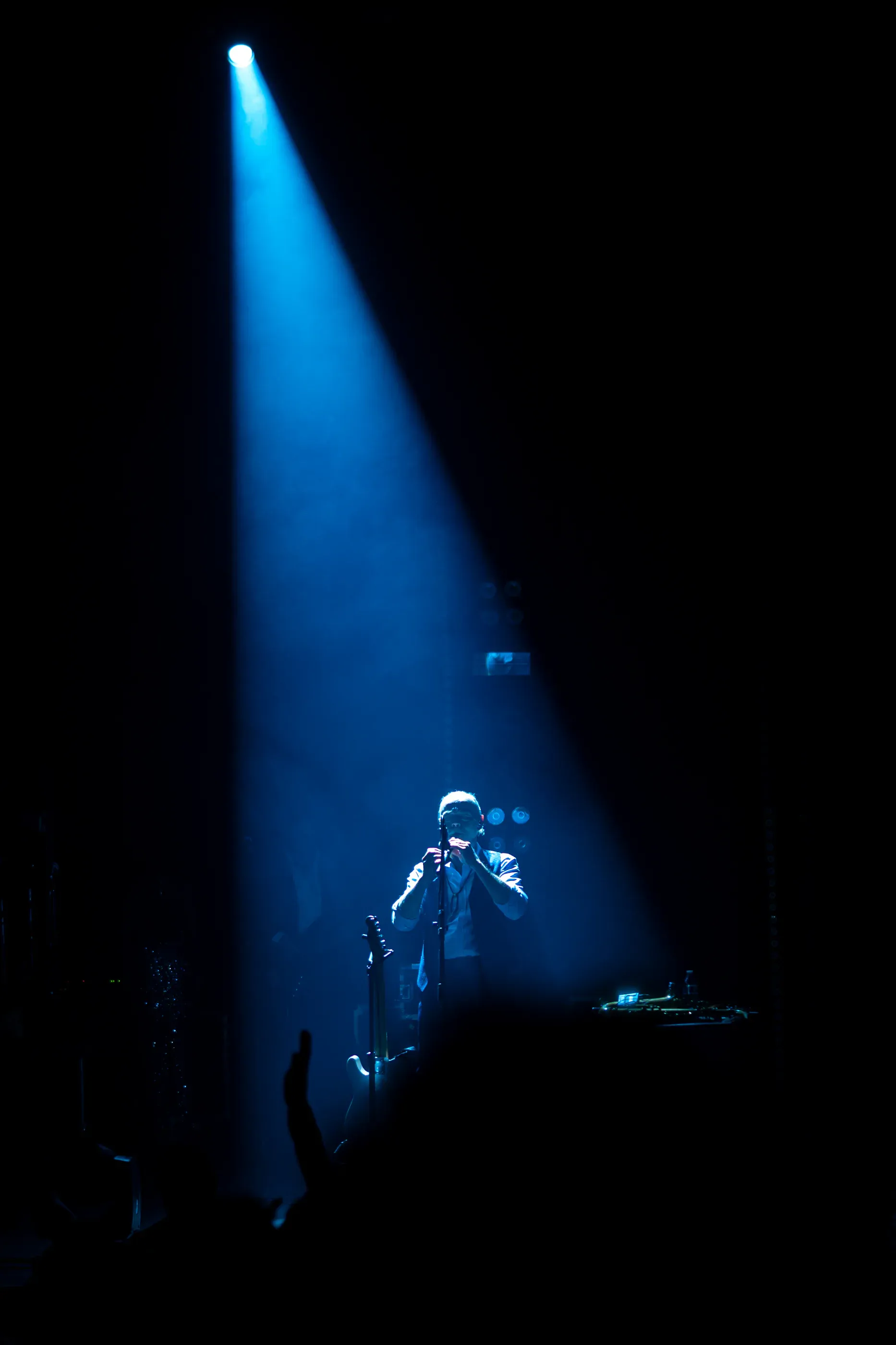 Performer stands beneath a single blue spotlight.
