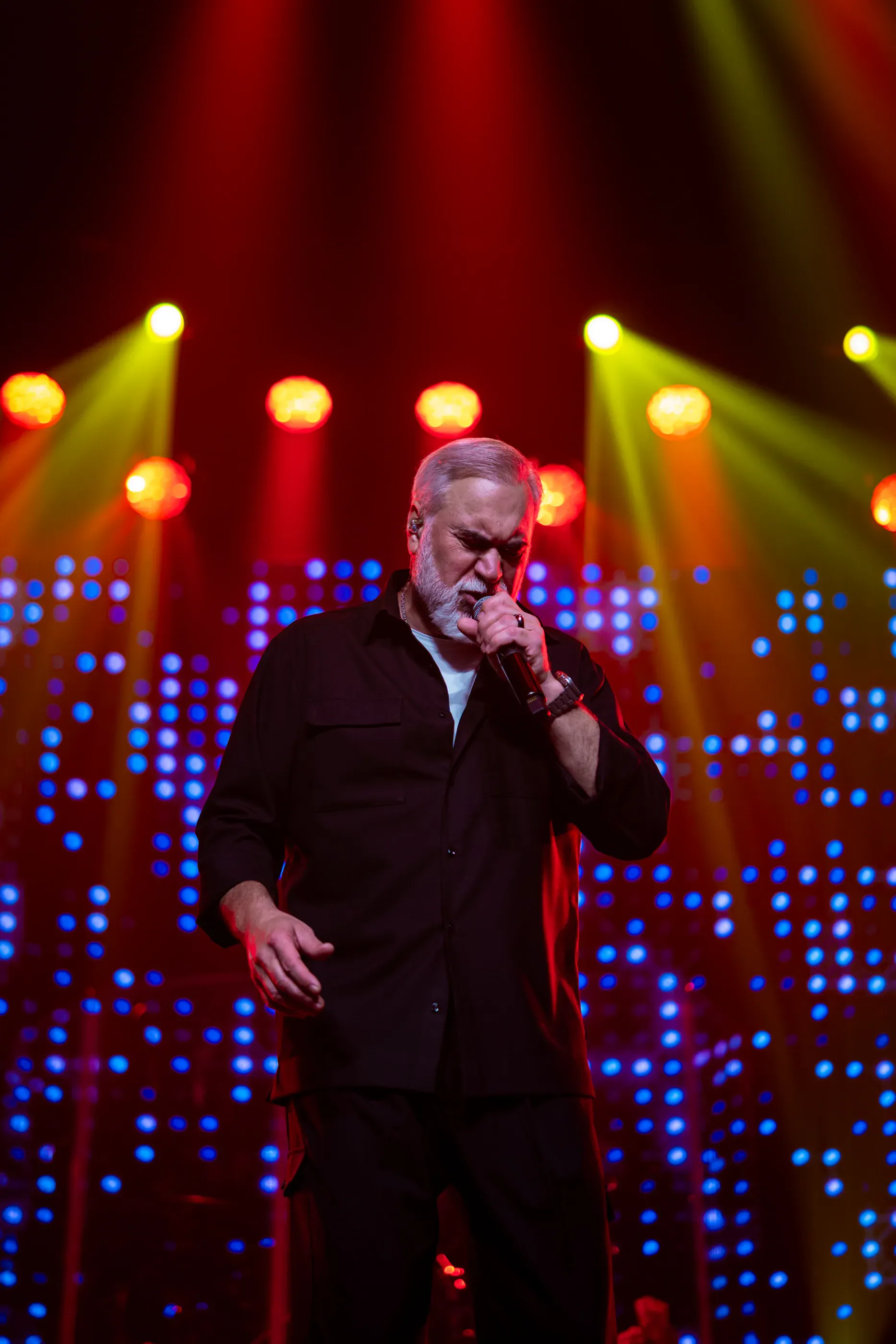 Valery Meladze sings in front of colorful stage lights.