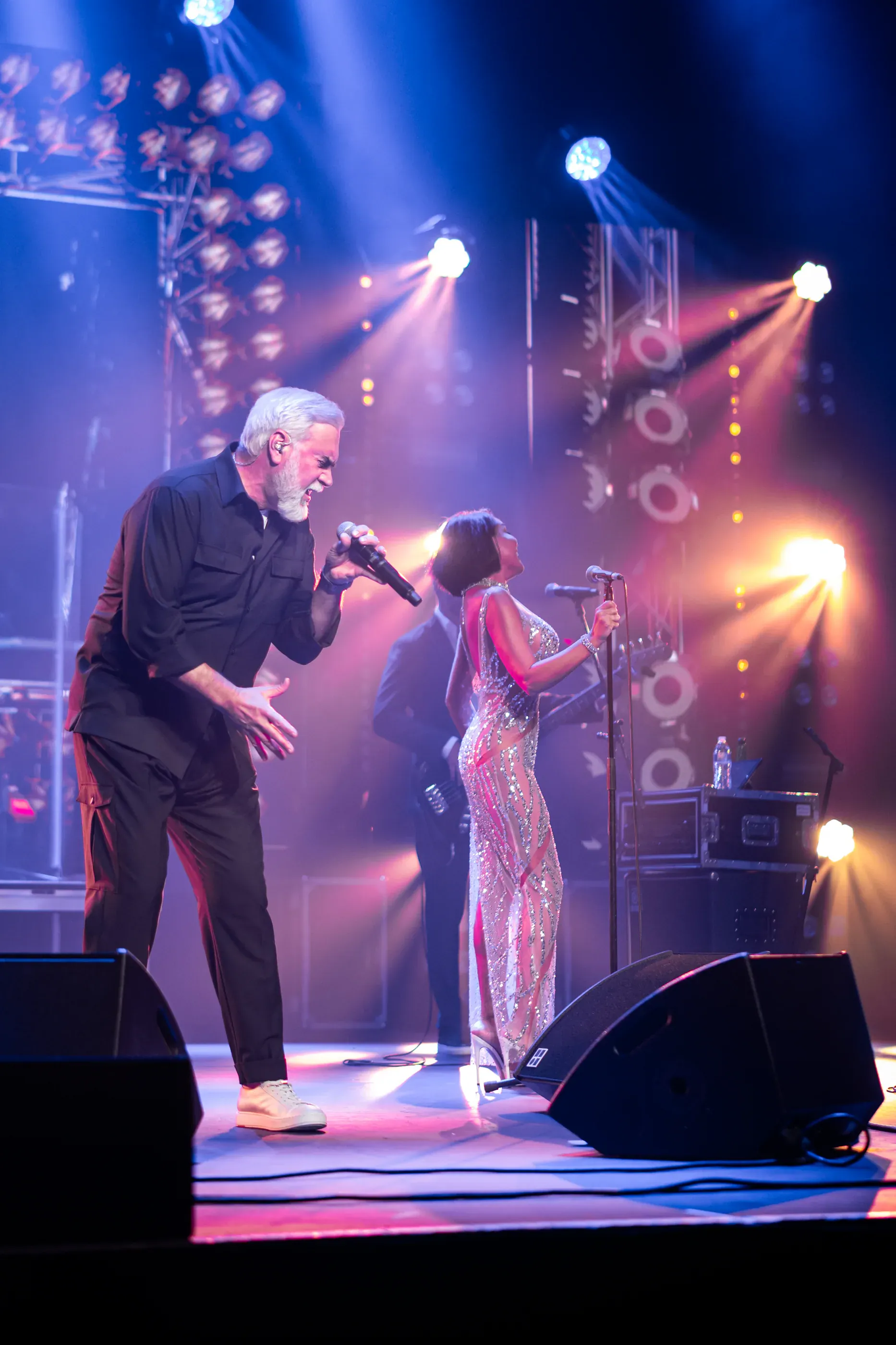 Two performers stand together on a brightly lit stage.