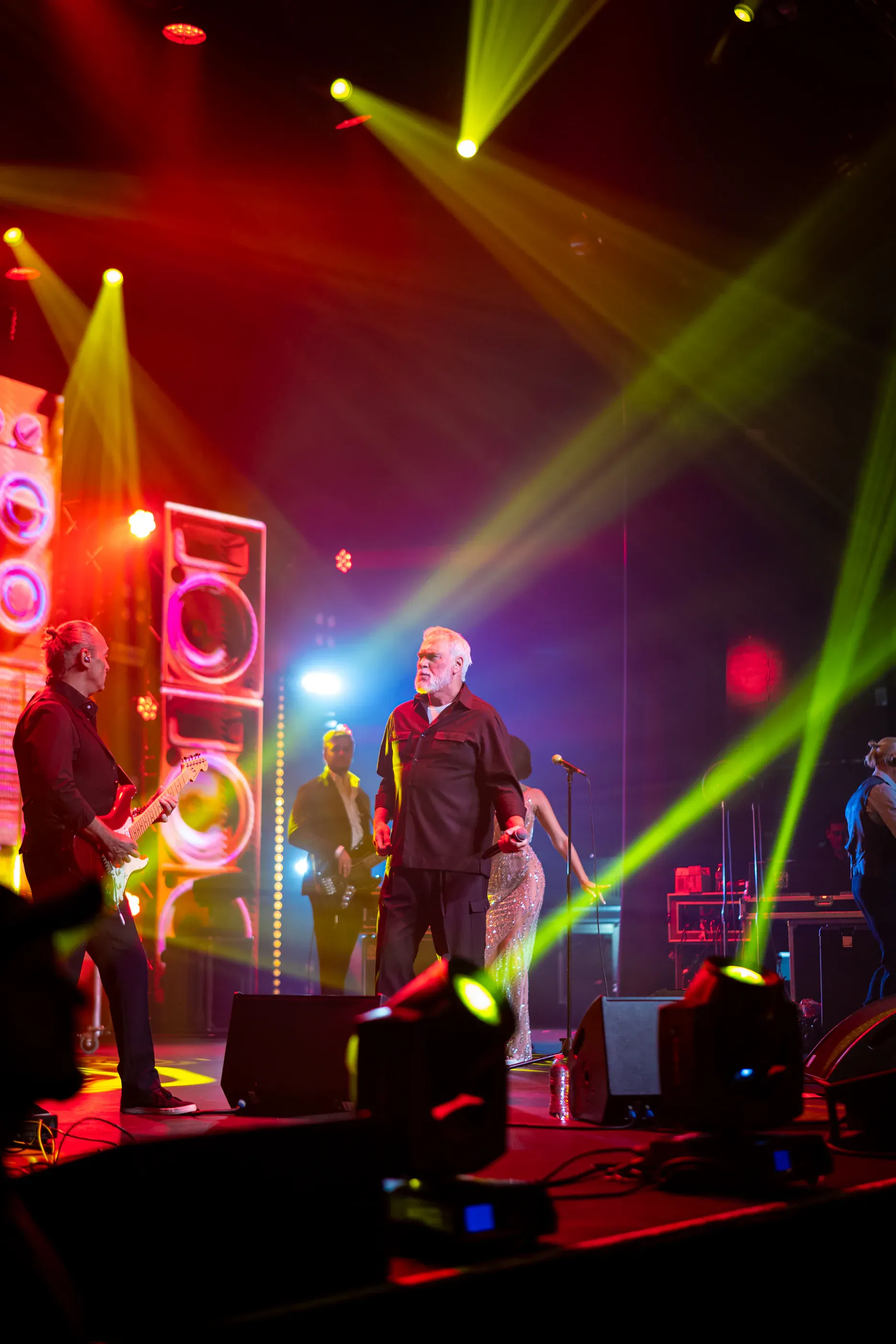 Singer performs on a stage with yellow light beams.
