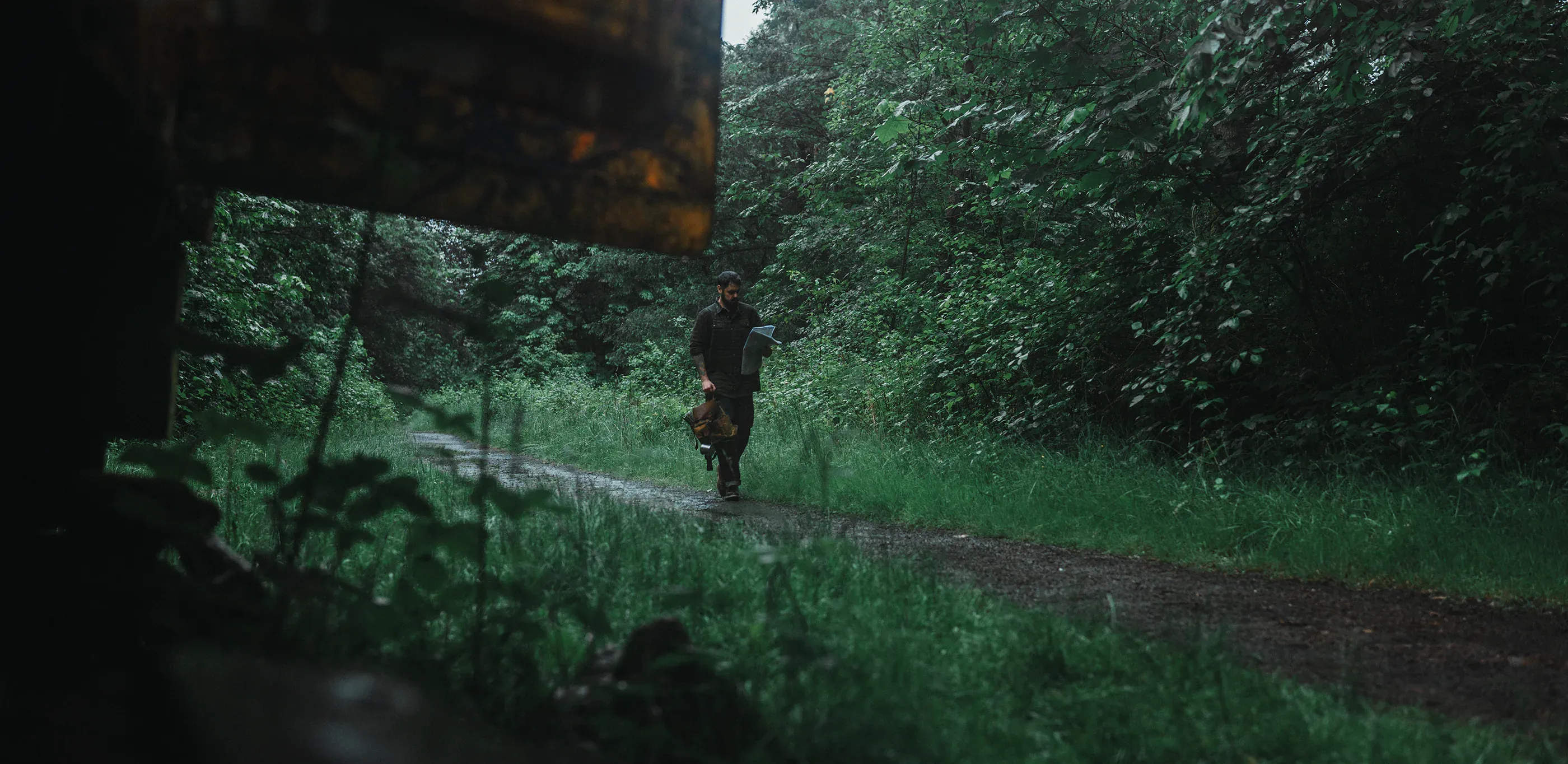 Small figure walks through a rainy green forest.