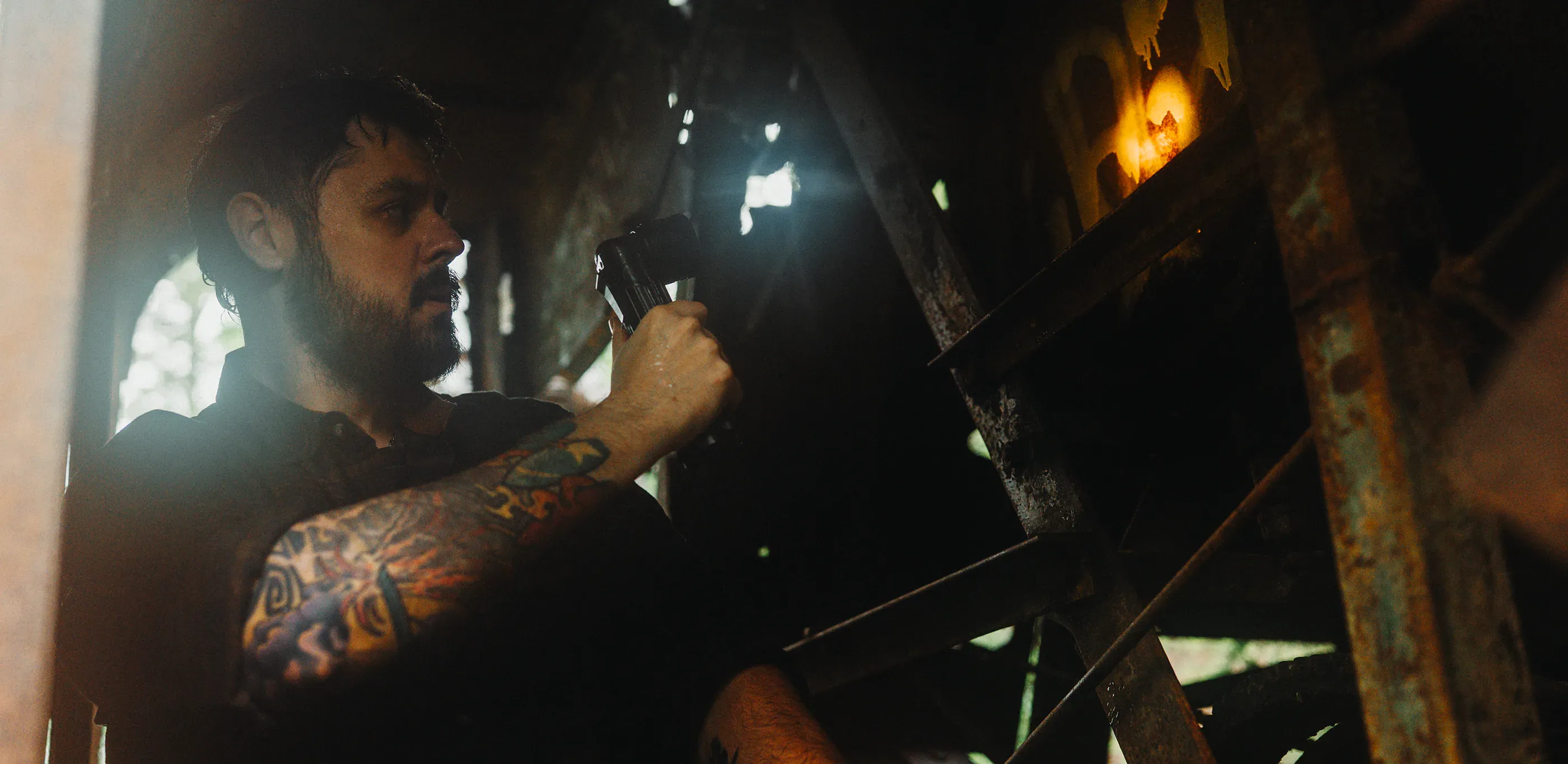 Person adjusts a flashlight inside a shadowed structure.